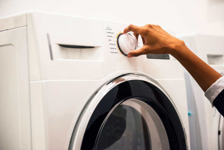Woman's hand adjusting the dial on a washing machine
