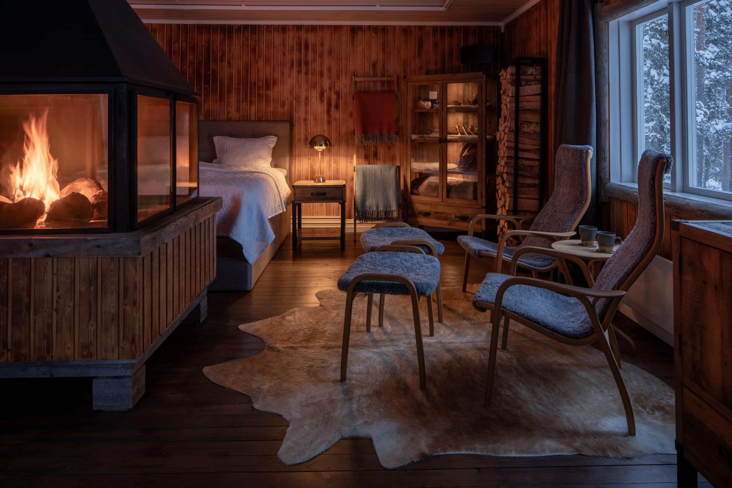 Binnen bij Loggers Lodge met fauteuils, open haard en houten muren in een gezellige Scandinavische sfeer.