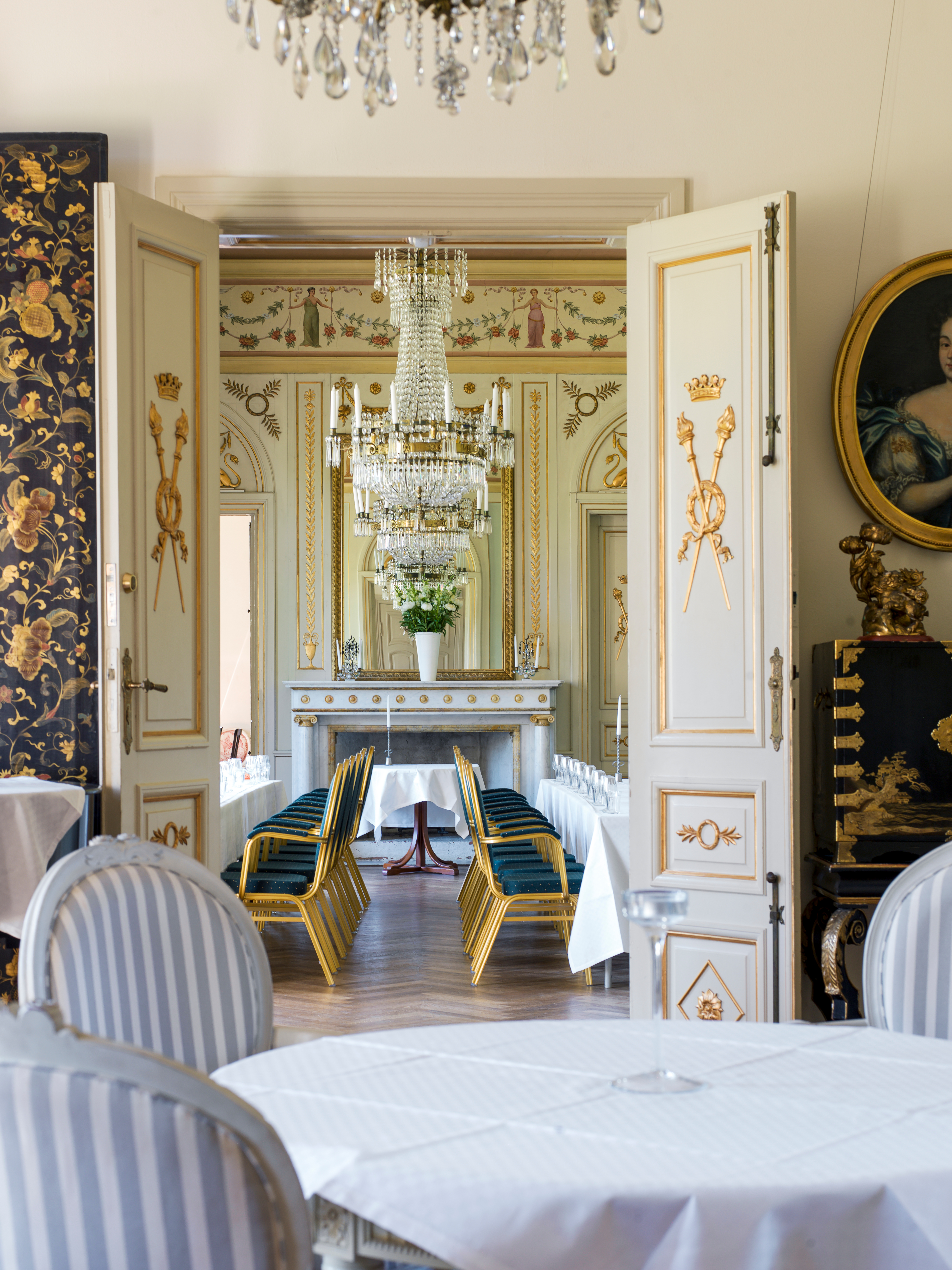 La salle à manger du château de Kronovall, avec ses lustres en cristal, ses tables élégamment dressées et ses intérieurs baroques français richement décorés.