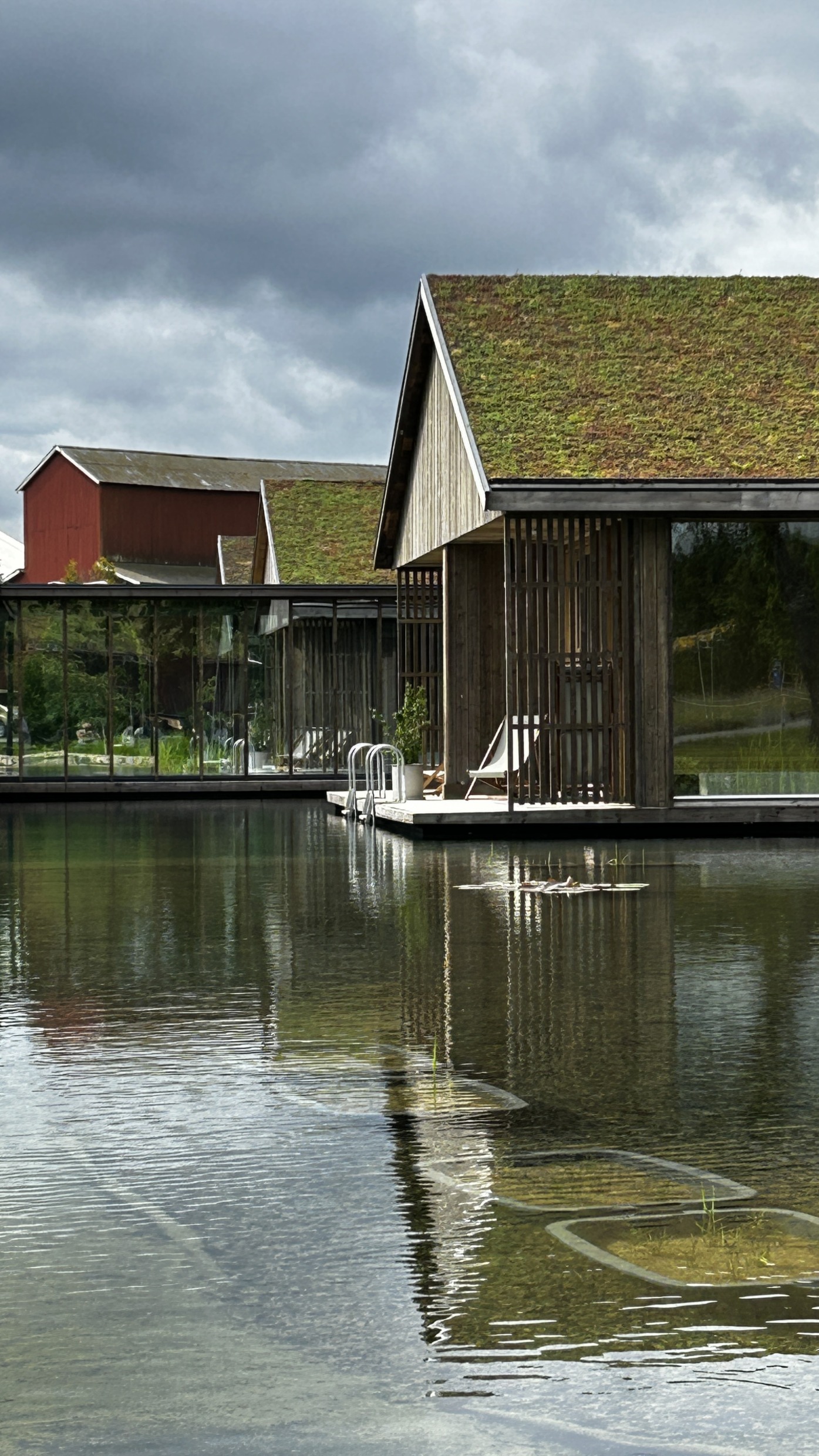 A wooden cabin with panoramic windows and a pool below the terrace.