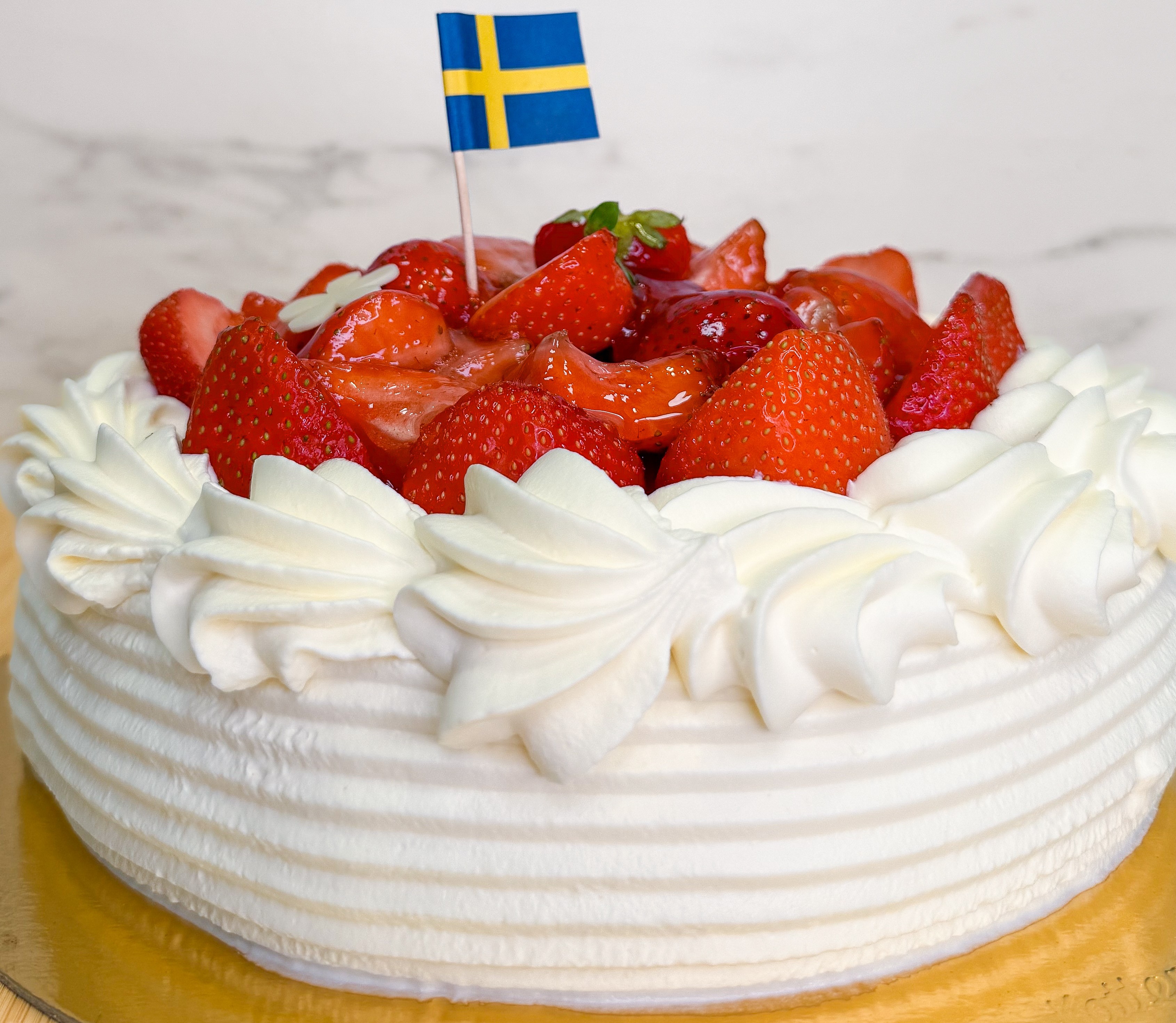 A strawberry cake with a Swedish flag on top.