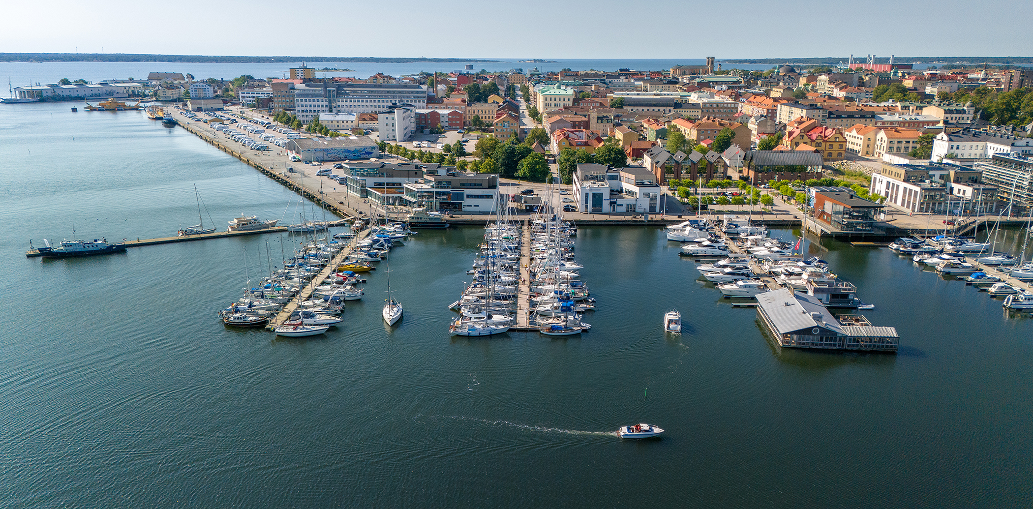Aerial view of Karlskrona and the guest harbour, with boats in the front and buildings in the back, all surrounded by water.