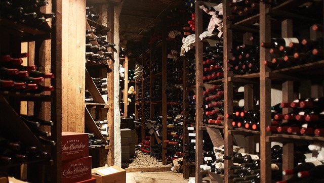 A dimly lit wine cellar at Restaurant 28+ in Gothenburg, featuring wooden shelves filled with wine bottles and stacked wooden crates.