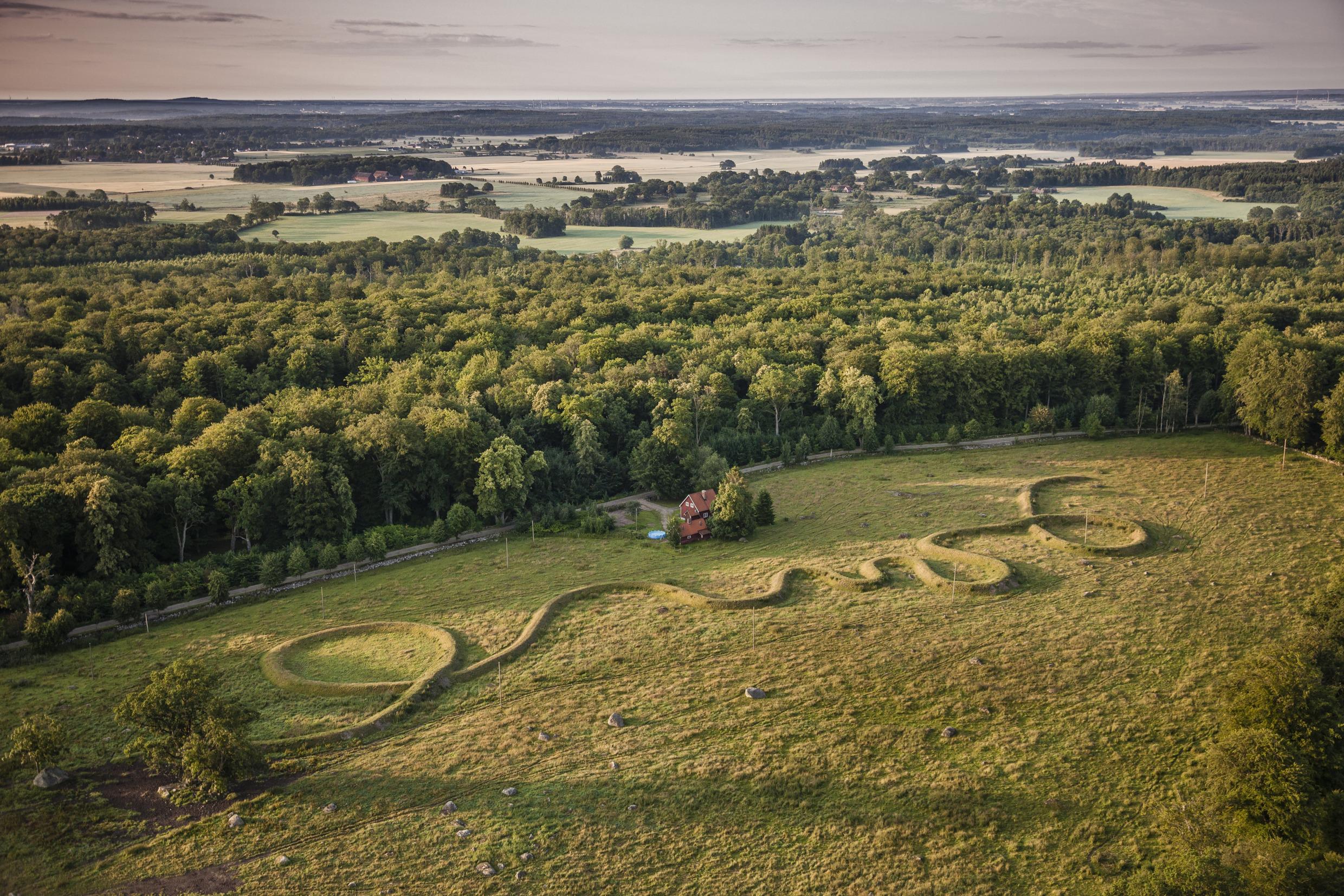 Aerial view of a 500 meter winding ridge of earth, stone and grass, a artwork called “Eleven Minute Line” in a sculpture park.