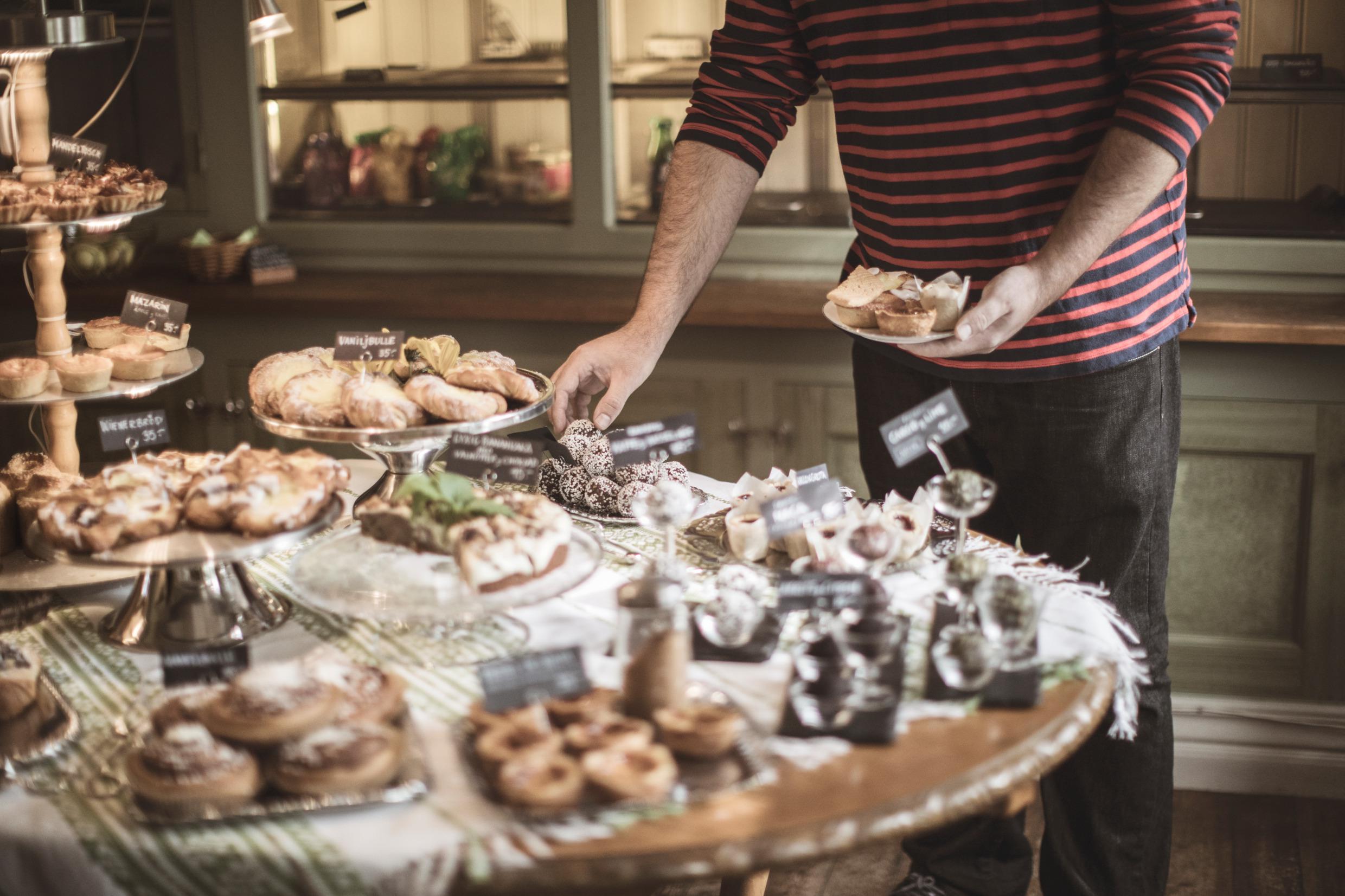 Iemand plukt gebakjes van een buffettafel met snoepjes.