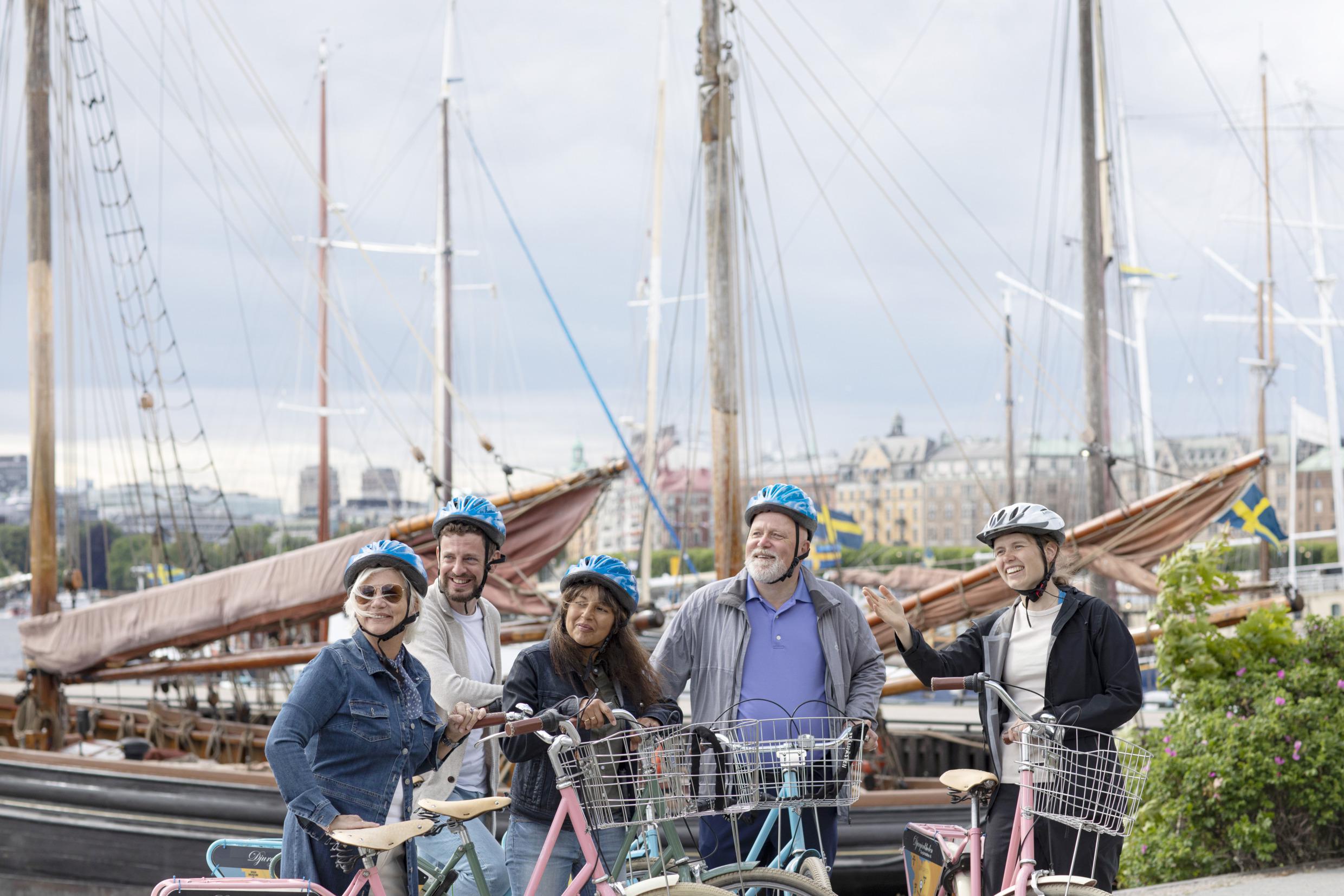 Eine Gruppe von Menschen steht neben ihren Fahrrädern und hört einem Städteführer zu.
