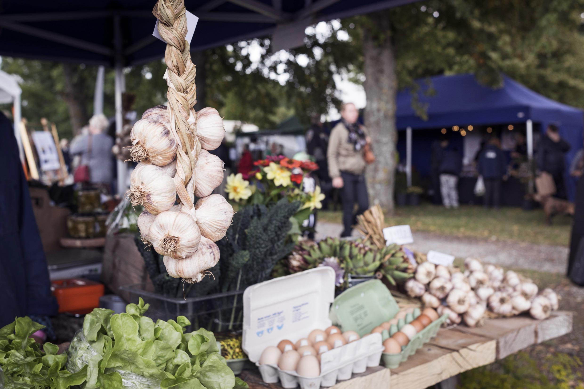 Ein Stand mit Knoblauch, Salat und Eiern auf einem Markt.