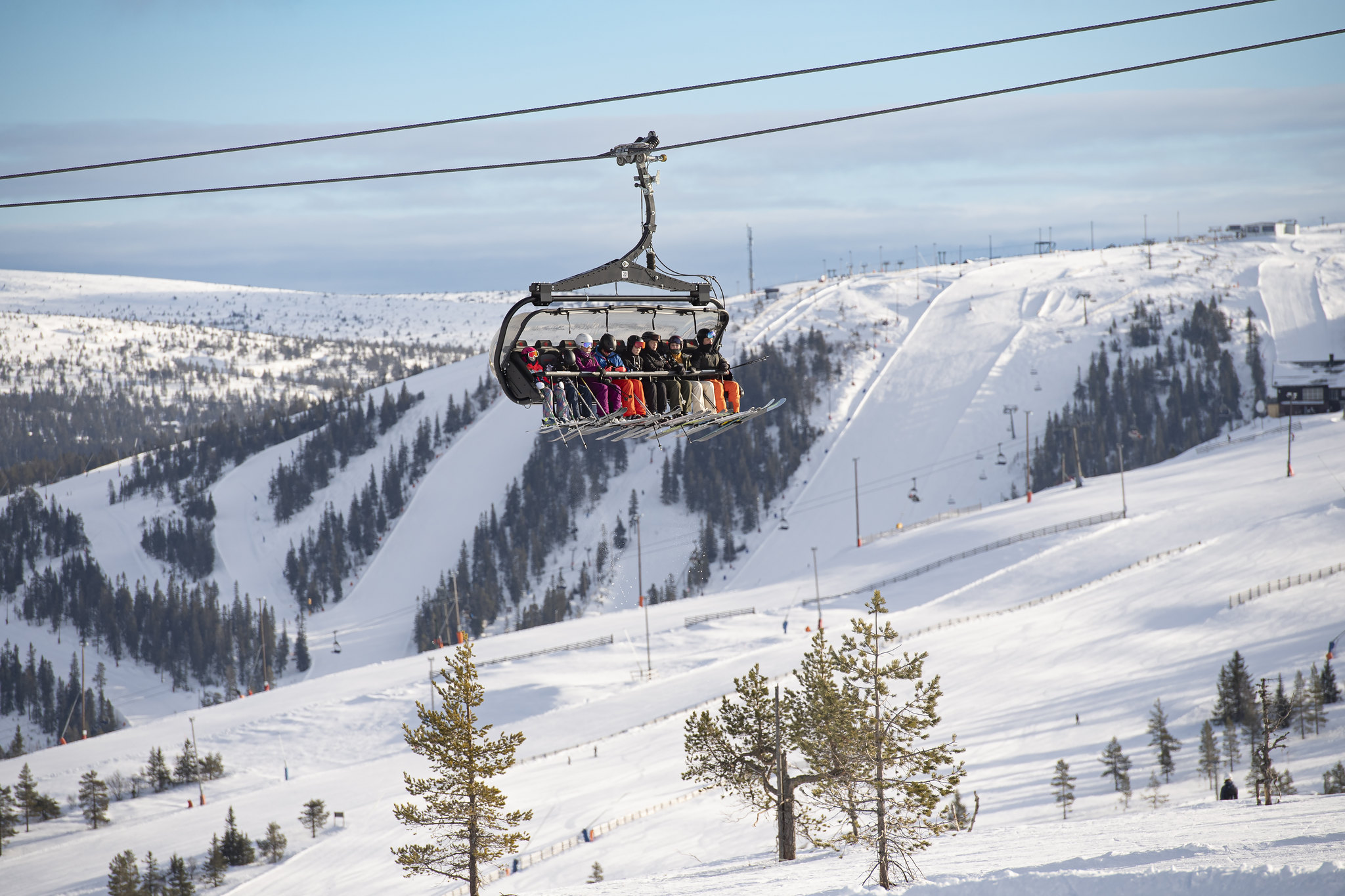 A full chairlift carries skiers above snowy slopes and pine trees in Sälen, Sweden’s largest ski resort area.