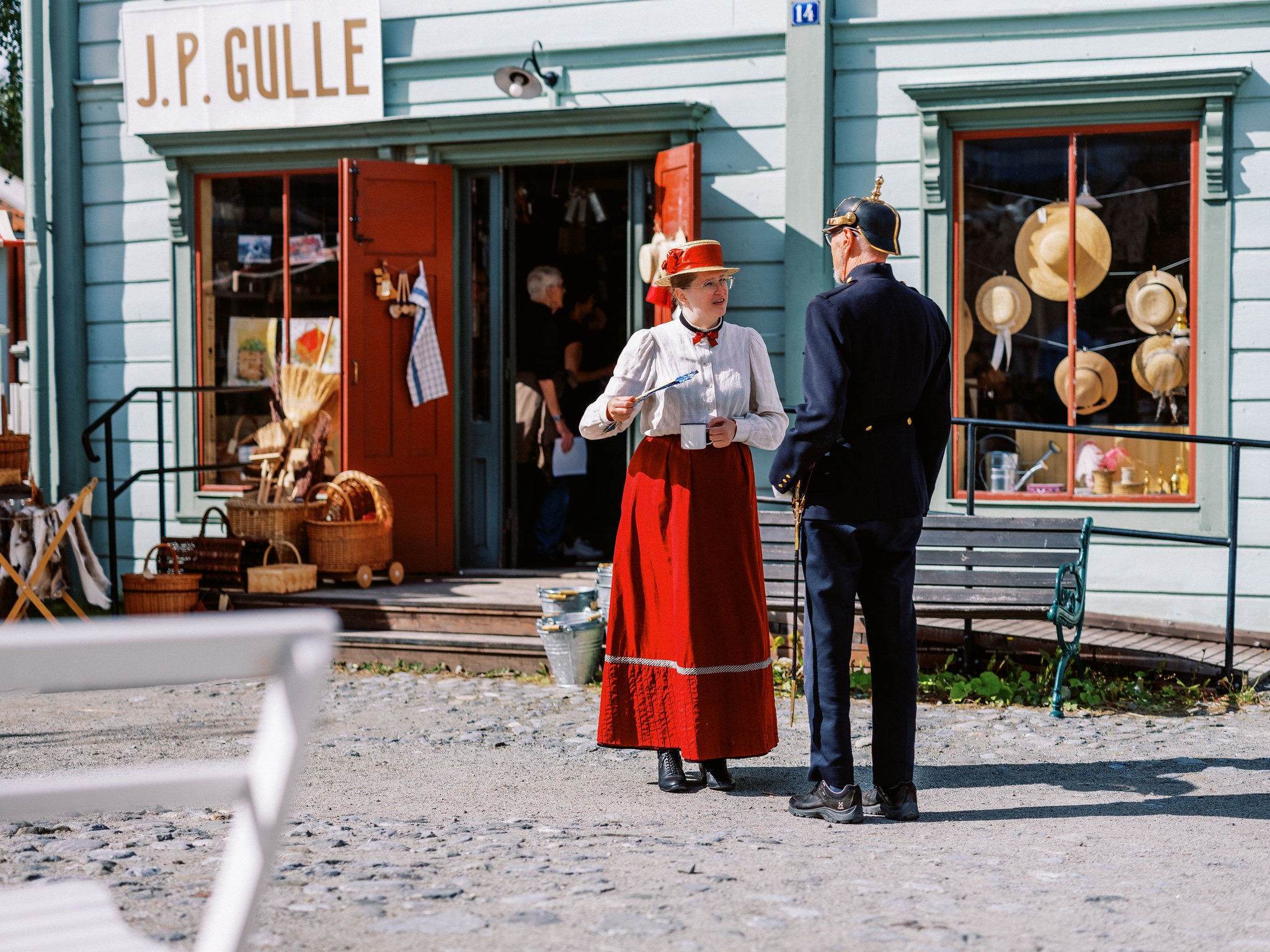 Mensen in historische kleren staan voor een vintagewinkel in het openluchtmuseum Jamtli in Östersund, Zweden – een levendige geschiedeniservaring in een traditionele setting.