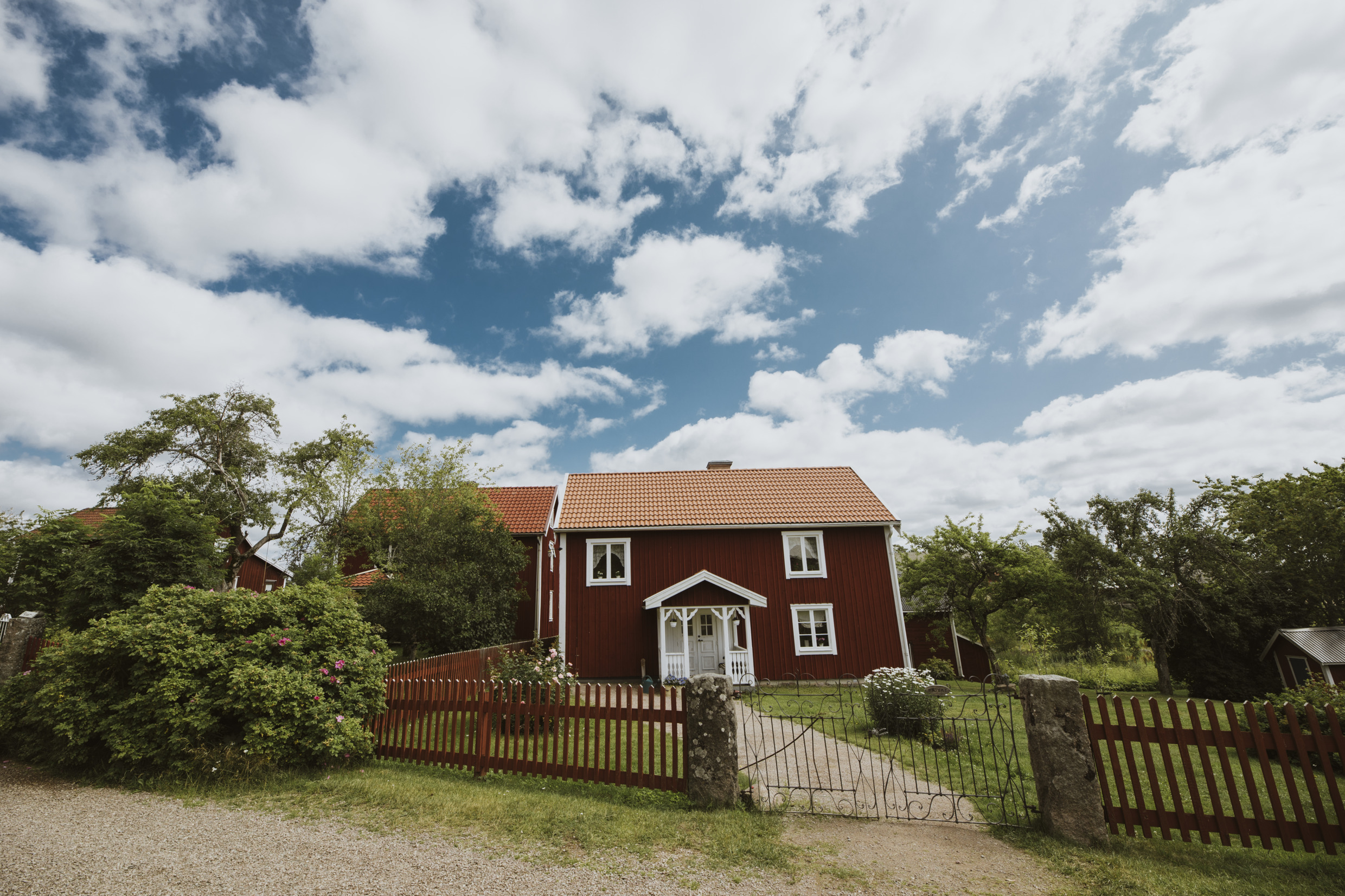 A red house with white corners and a large garden on a summer day