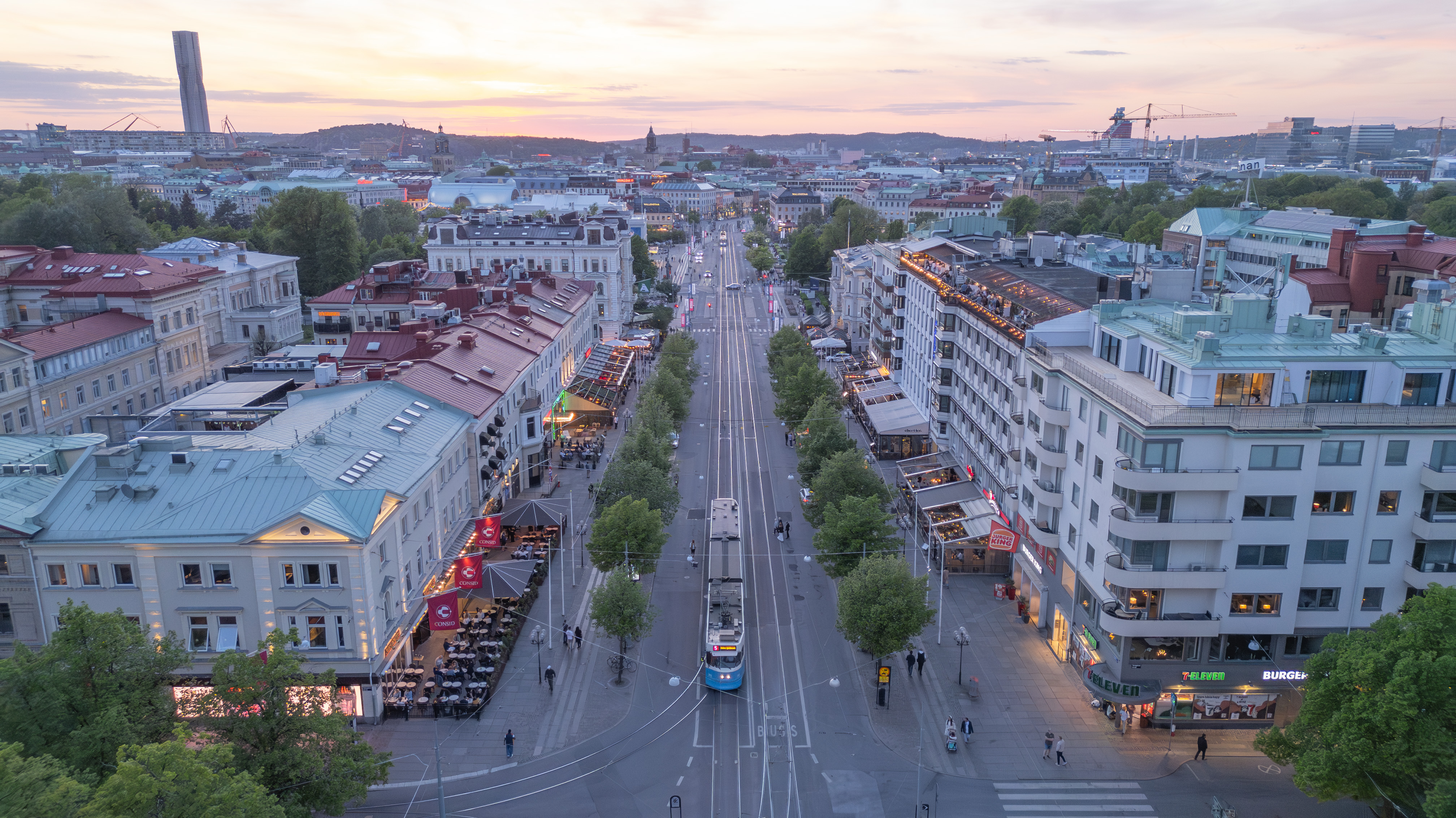Aerial view of Avenyn, Gothenburg’s main boulevard, with a tram travelling along the tree-lined avenue at sunset.