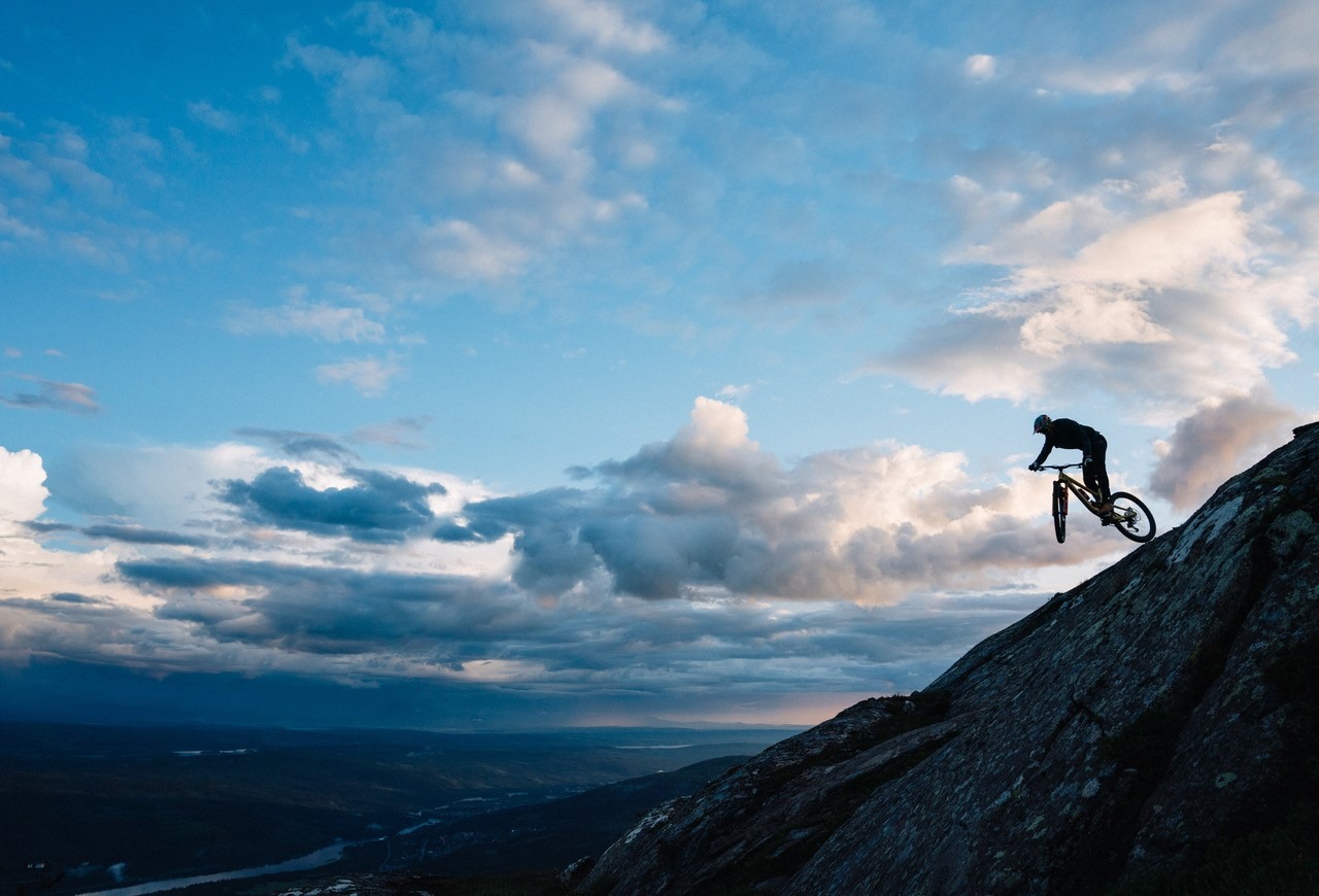 Die Silhouetten eines Radfahrers auf einem Berggipfel an einem Sommerabend.