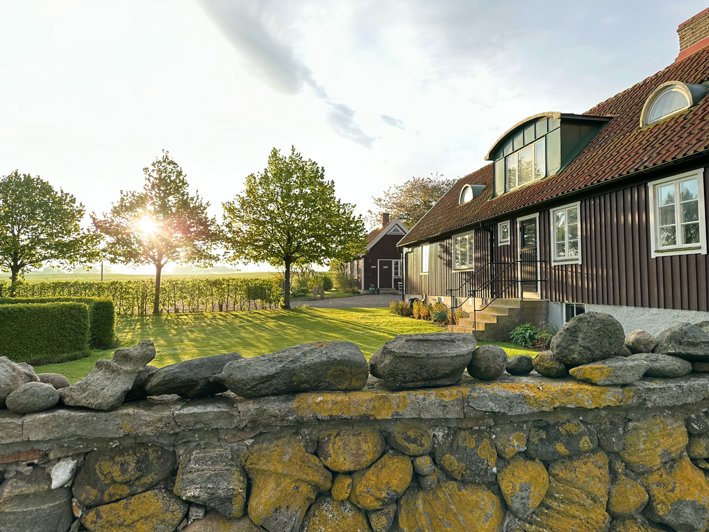 Un bâtiment traditionnel de Scanie qui constitue une partie du musée Birgit Nilsson à Svenstad, entouré de champs et d'arbres dans la lumière du soir.