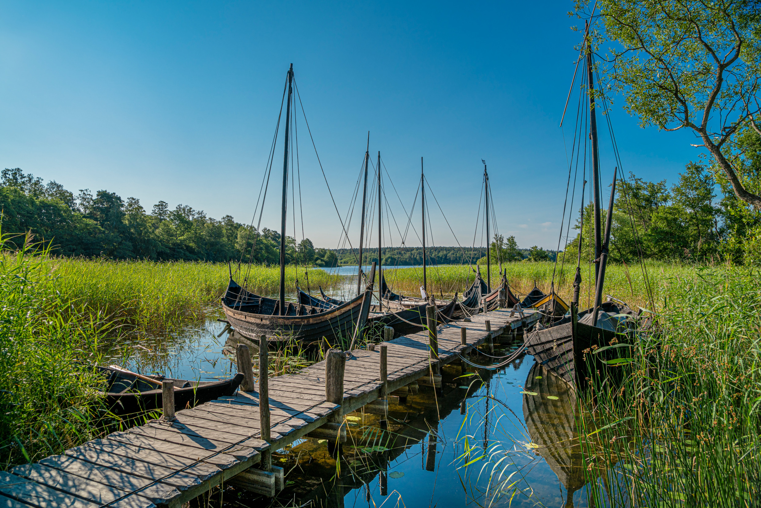 Ein See mit am Ufer vertäuten Wikingerschiffen.