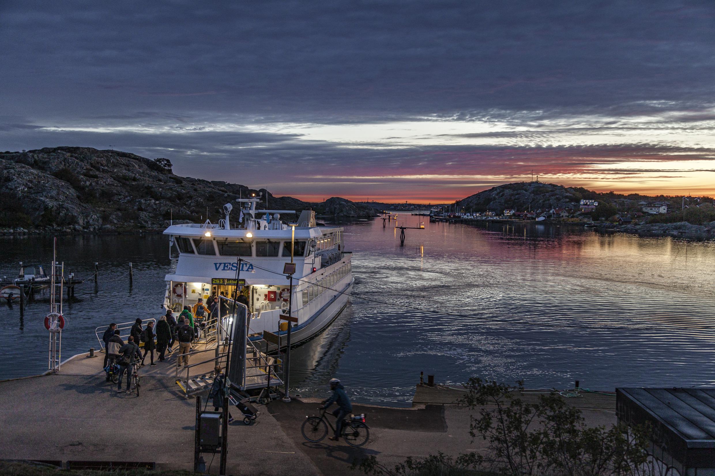 Bij zonsondergang legt een veerboot aan bij een kleine pier.