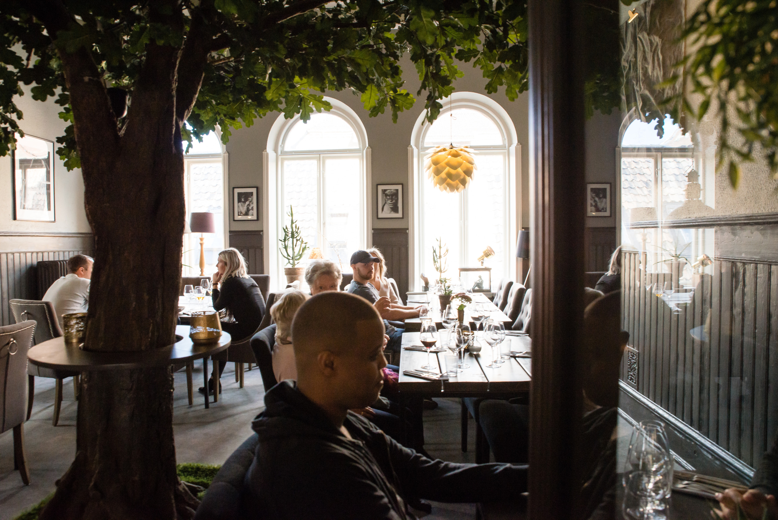 Gäste speisen unter Bäumen im modernen Restaurant Creo in Helsingborg.