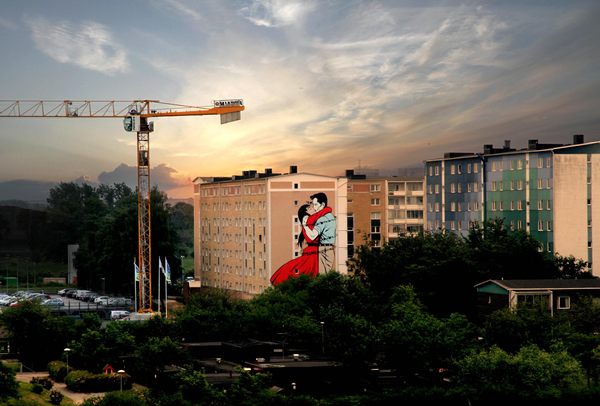 A large mural on the wall of an apartment building in Malmö. The street art piece depicts a man and woman kissing and embracing each other.