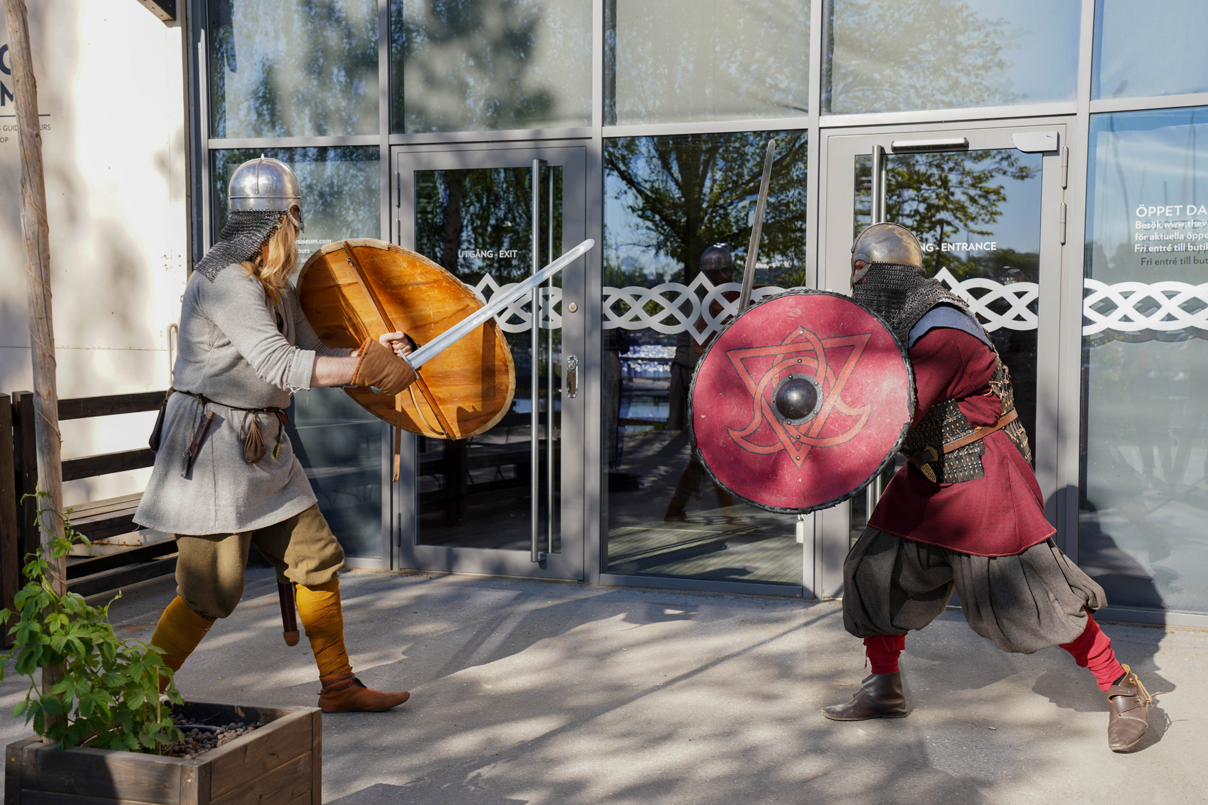 Twee mannen verkleed als Vikingen doen alsof ze vechten met zwaard en schild in het Vikingmuseum.