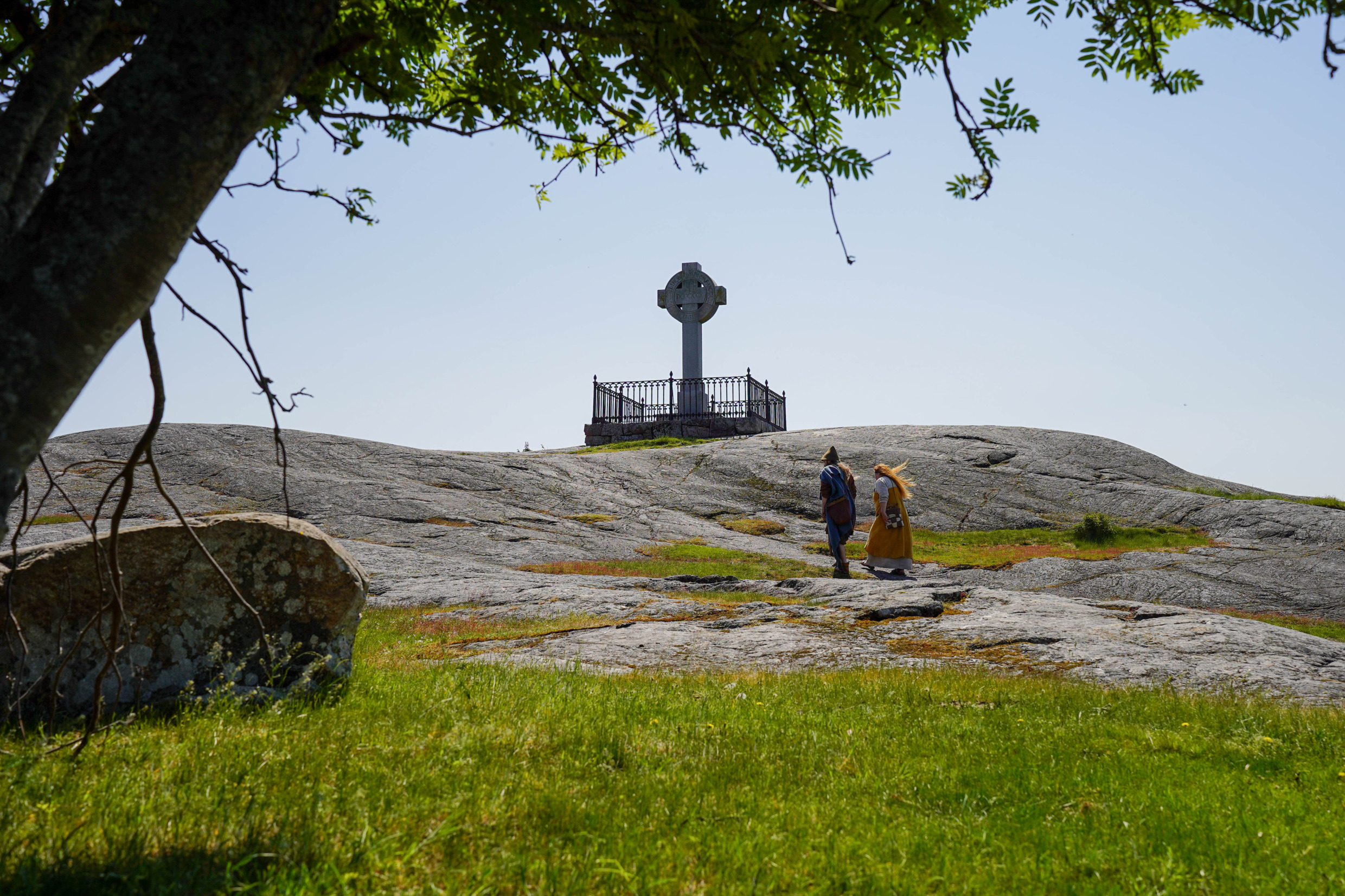 Twee Vikingen lopen een heuvel op naar een Vikingmonument in Birka, het Vikingdorp.