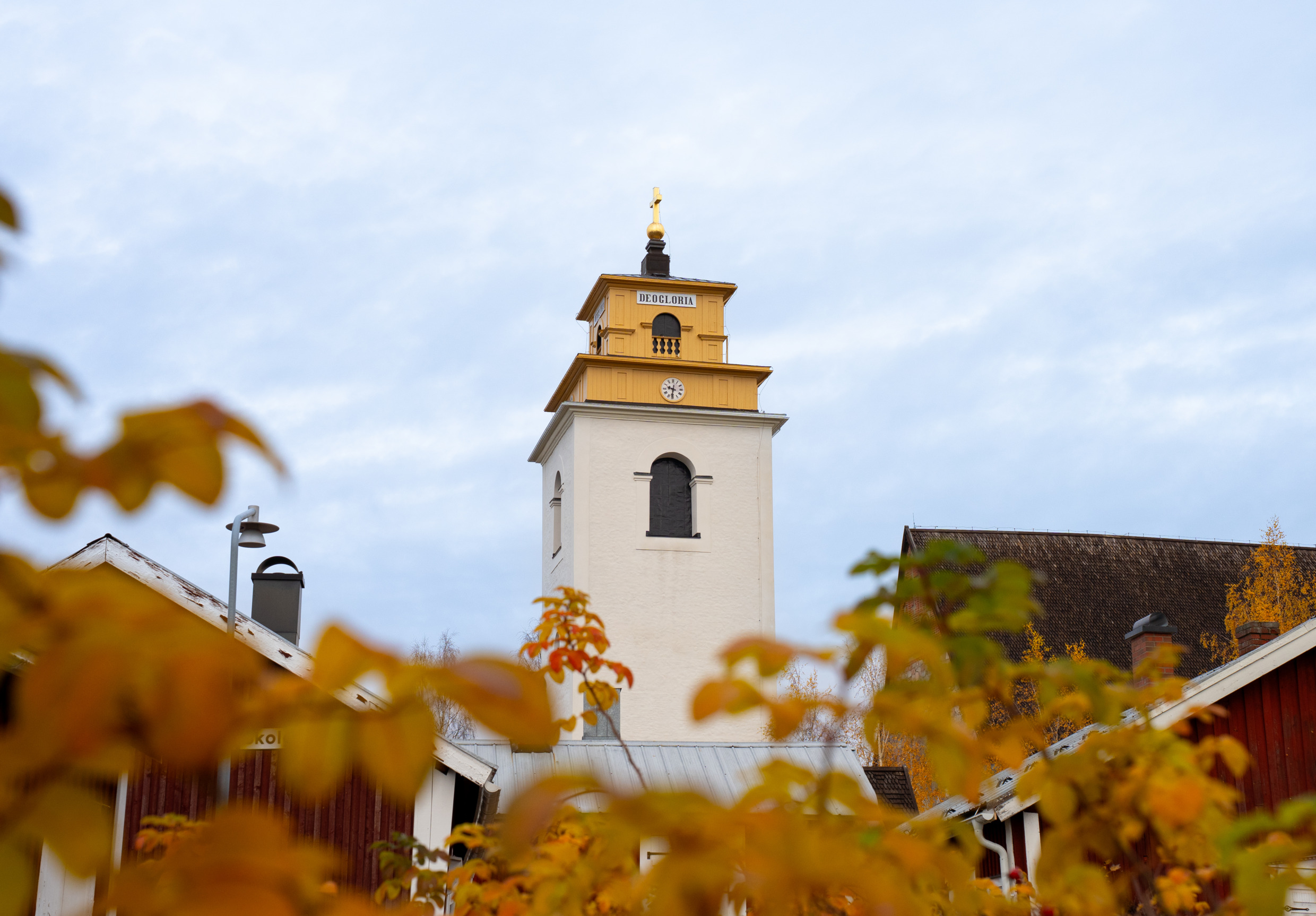 A white, tall church surrounded by red cottages with white corners.