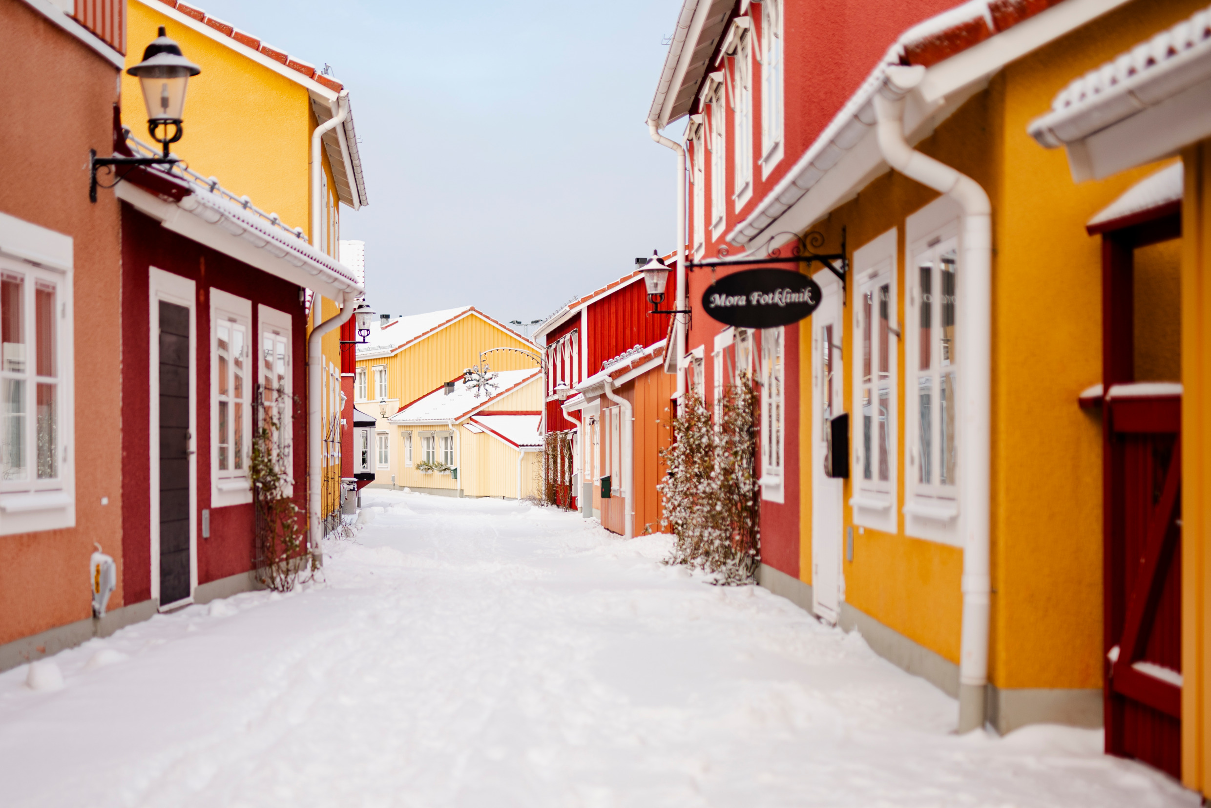 Eine schneebedeckte Straße in Mora, Dalarna gesäumt von bunten kleinen Häusern.