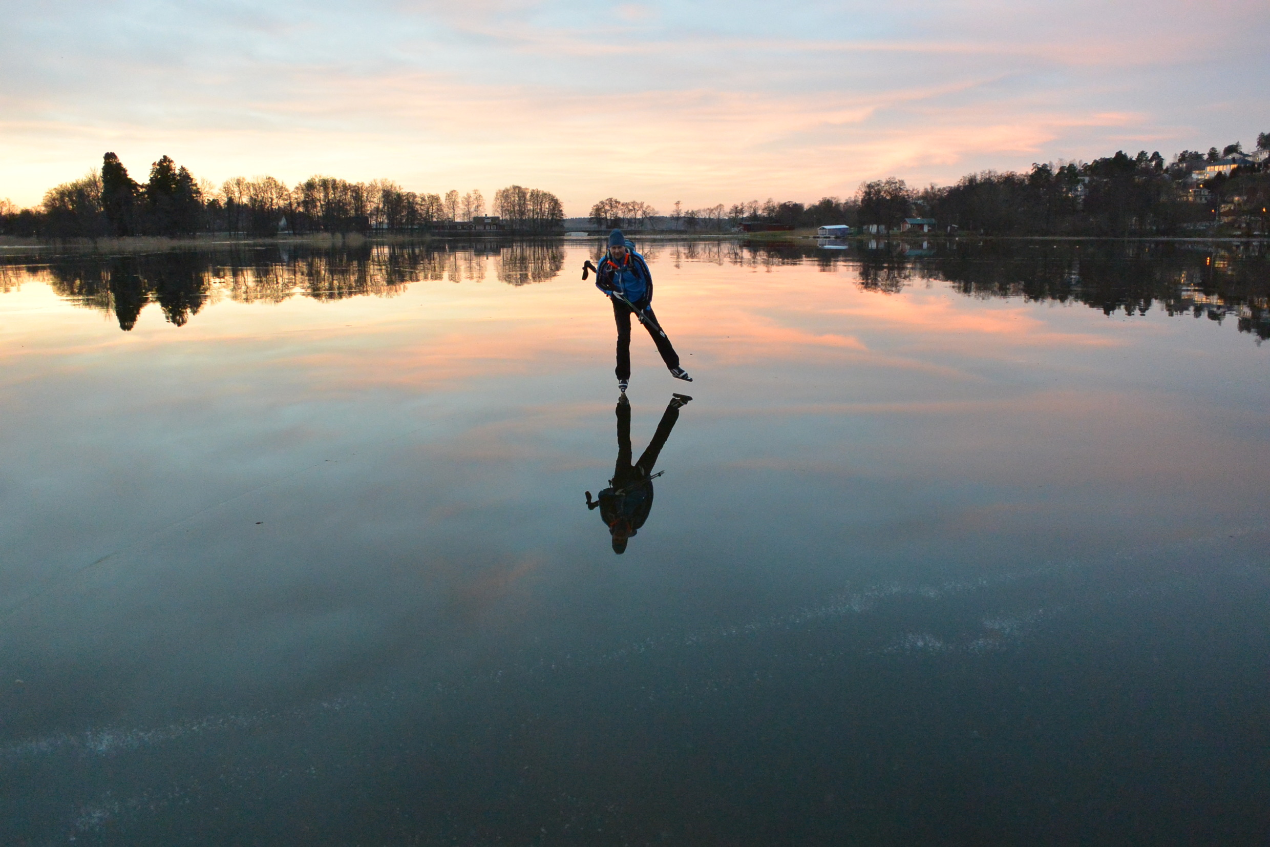 A person ice skating on a frozen lake at dusk.