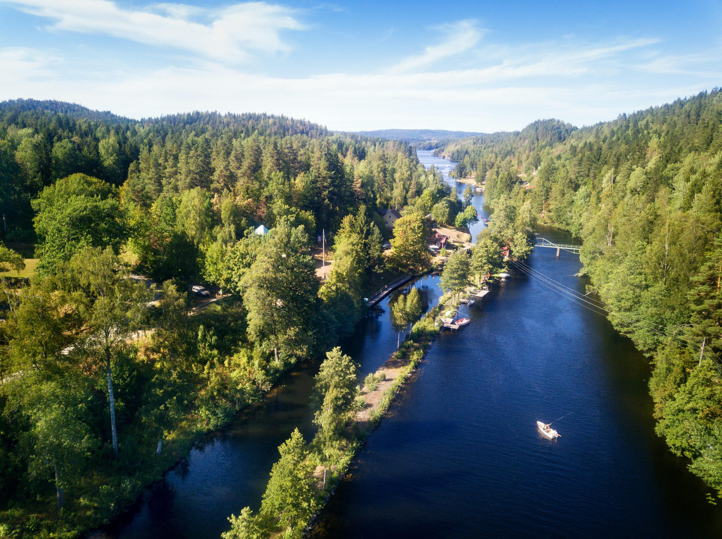 Luchtfoto van het Dalslandkanaal omgeven door bos, met kleine boten op het water en kades langs de met bomen begroeide oevers.