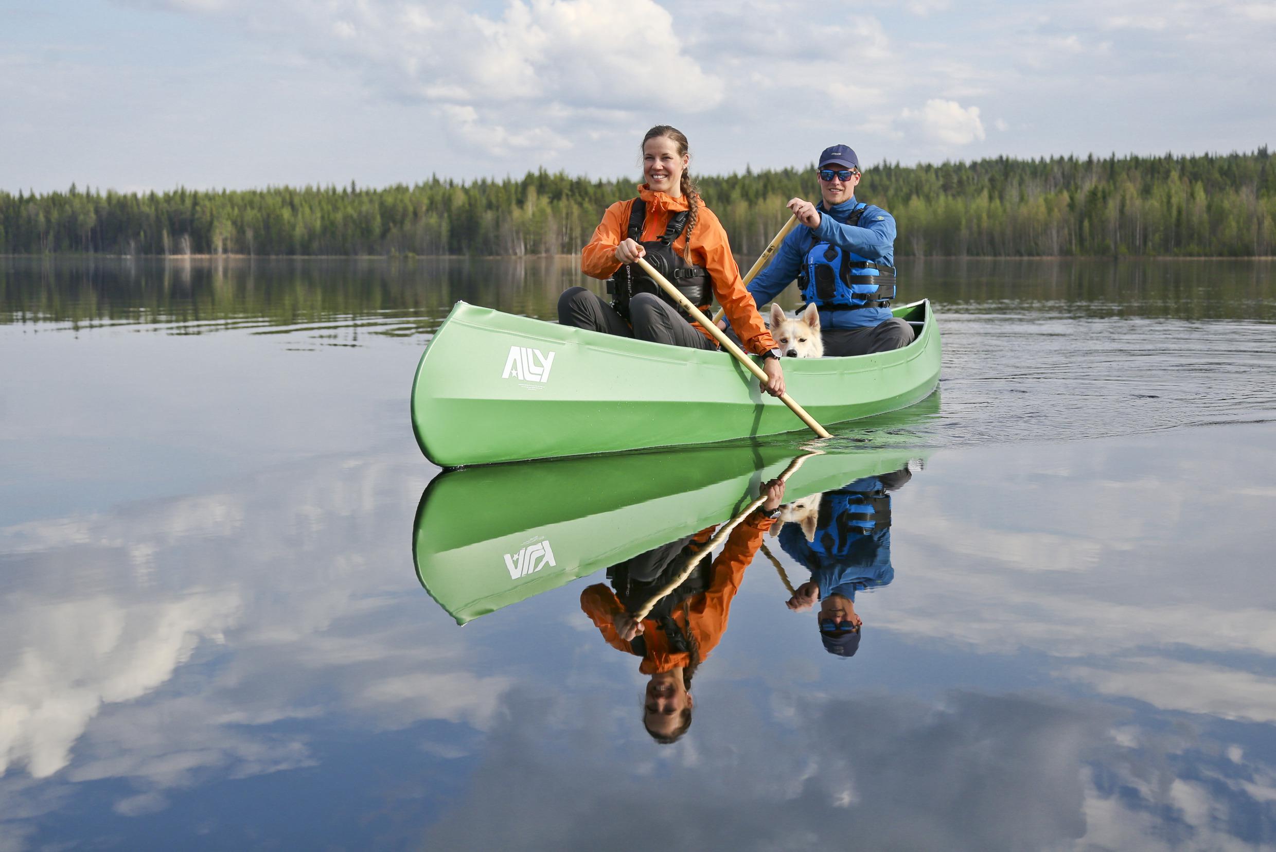 Een man en een vrouw die samen kanoën in water omringd door bos.