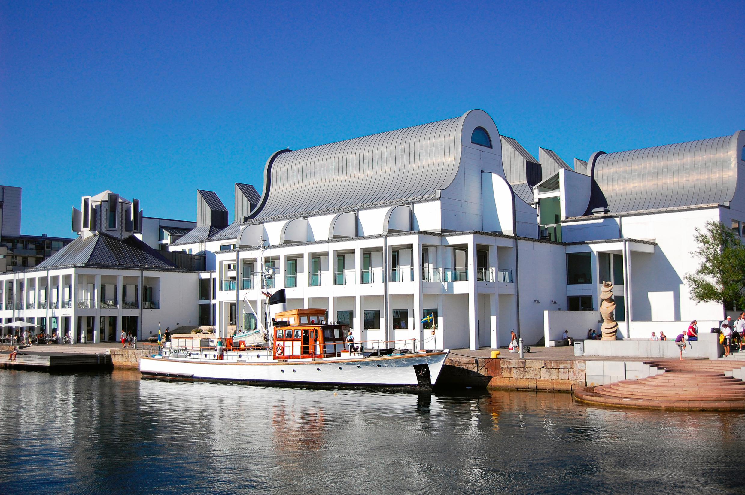 Ein weißes Holzboot steht for einem weißen modernen Gebäude.