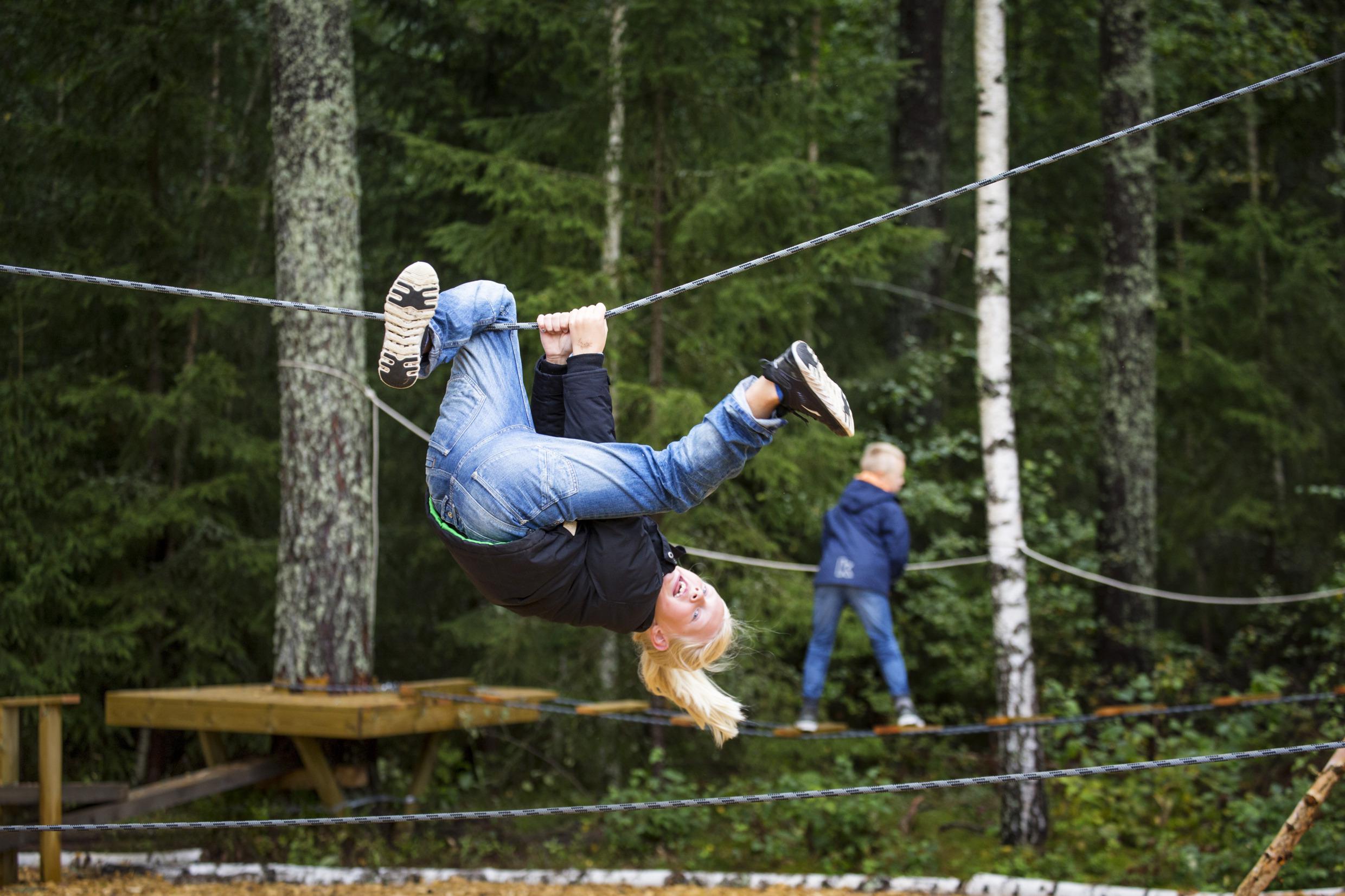 Deux enfants s'amusent sur un parcours d'accrobranches.