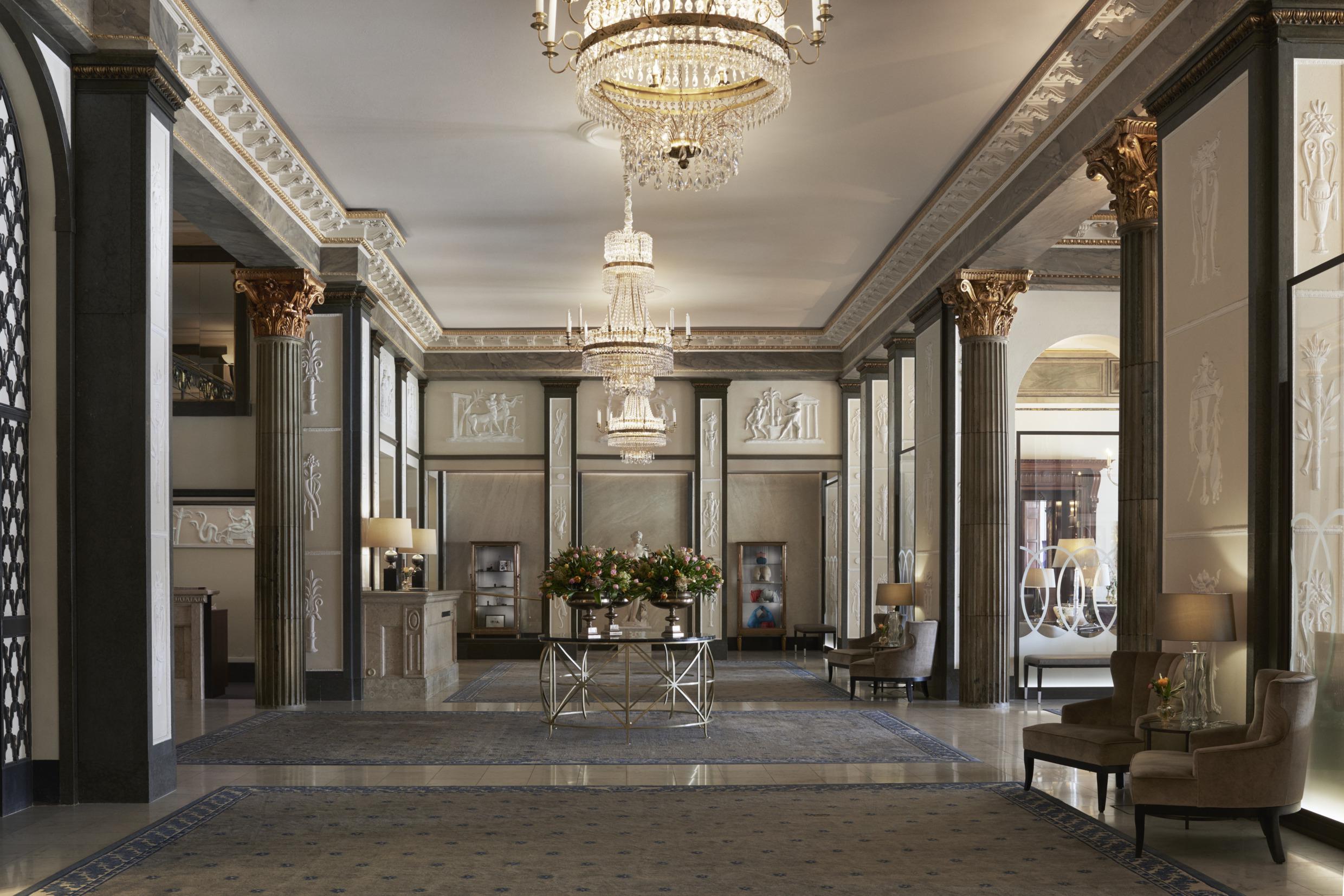 The wide lobby of Grand Hotel in Stockholm, with chandeliers and groups of sofa chairs.