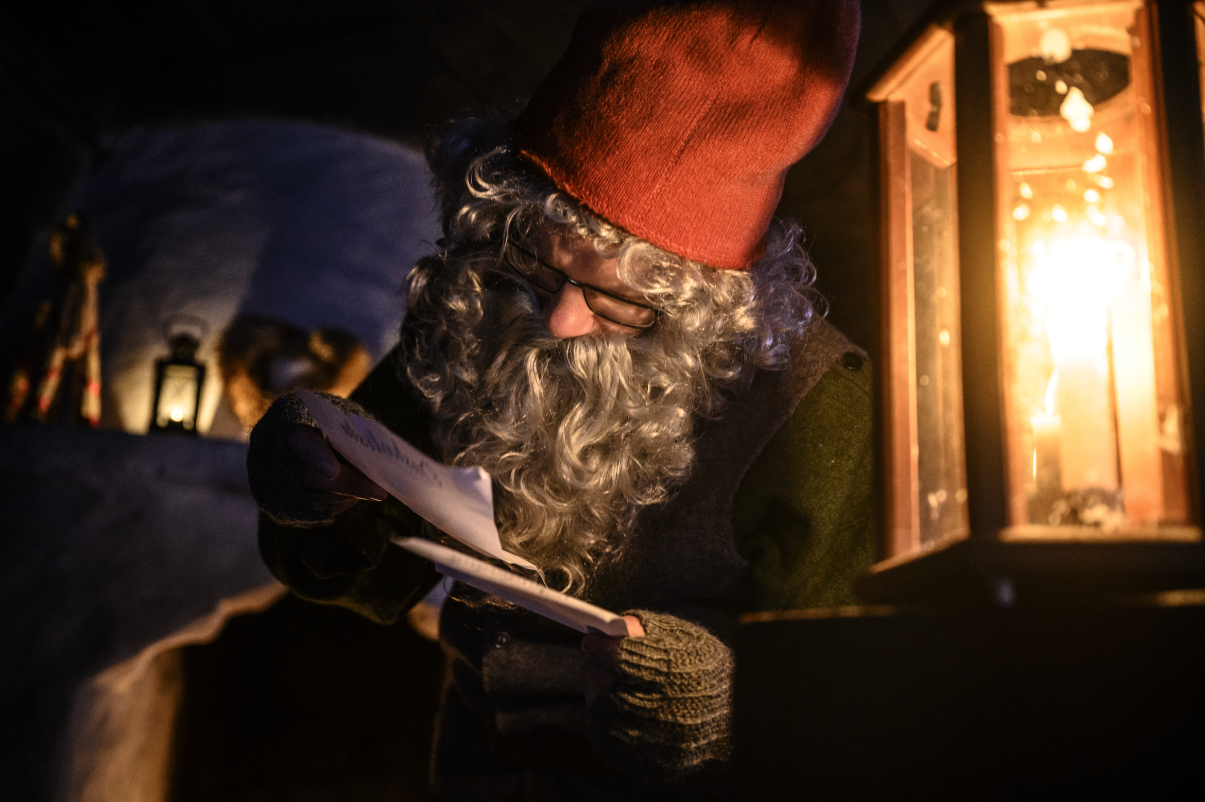 Un homme déguisé en Père Noël lit une lettre à la lumière d'une lanterne au marché de Noël de Jamtli.
