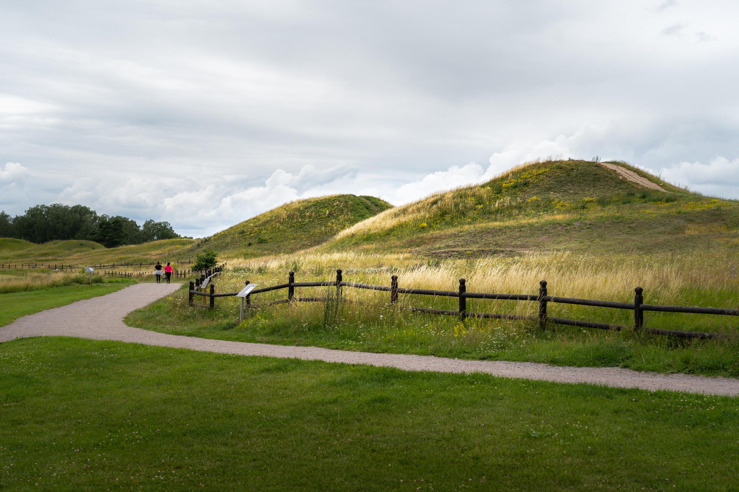 Une allée de gravier est entourée de grands monticules couverts d'herbe.
