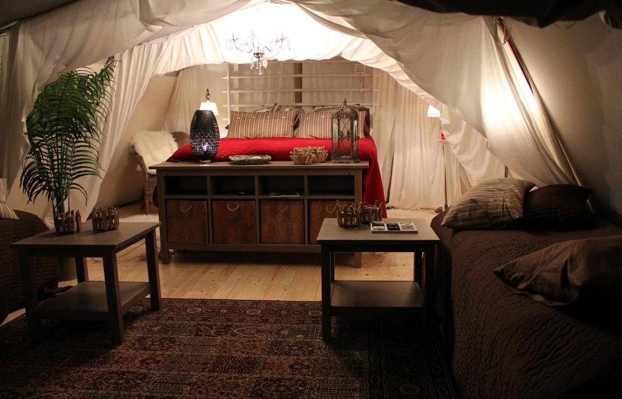 Ein Glampingzelt im Böda Sand Beach Resort mit schöner Dekoration und Möbeln aus dunklem Holz.Ein Kronleuchter hängt am Zeltdach und spendet Licht.