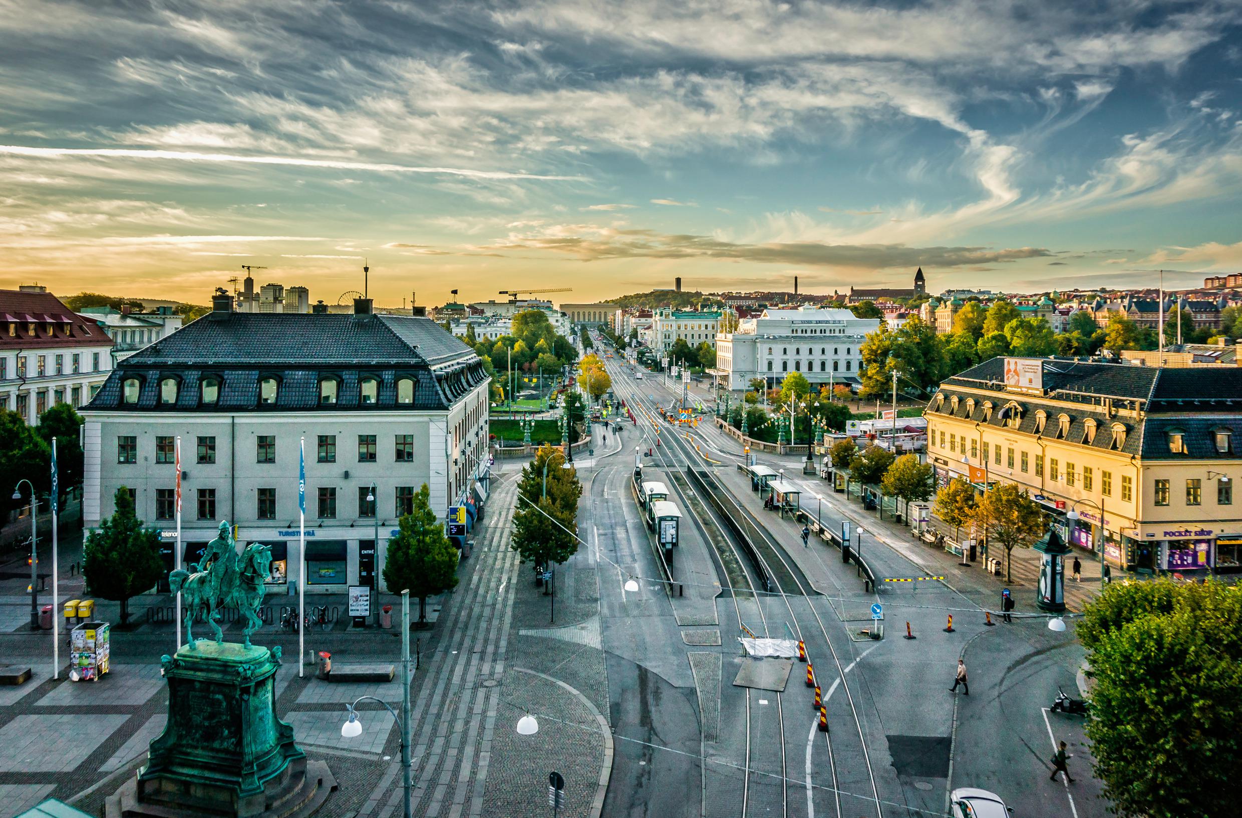 Een schilderachtig uitzicht op de stad Göteborg, met bijna lege straten, gebouwen en een kleurrijke avondrood op de achtergrond.