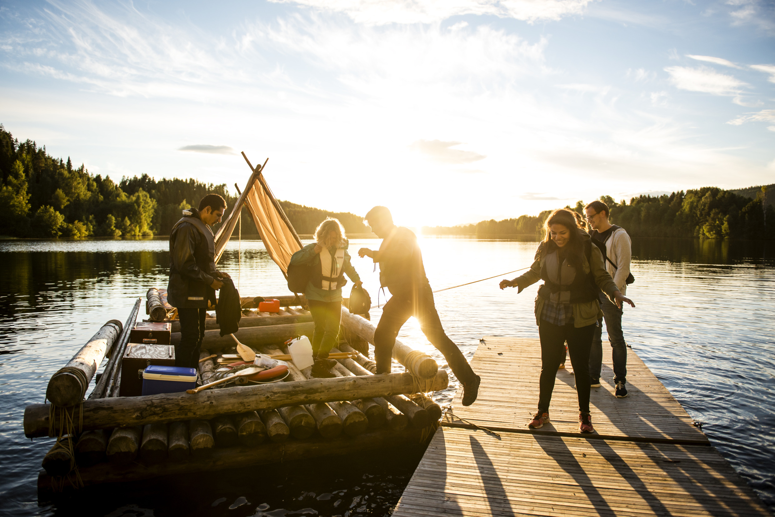 Vijf personen staan klaar om op een zelfgemaakt vlot te stappen.