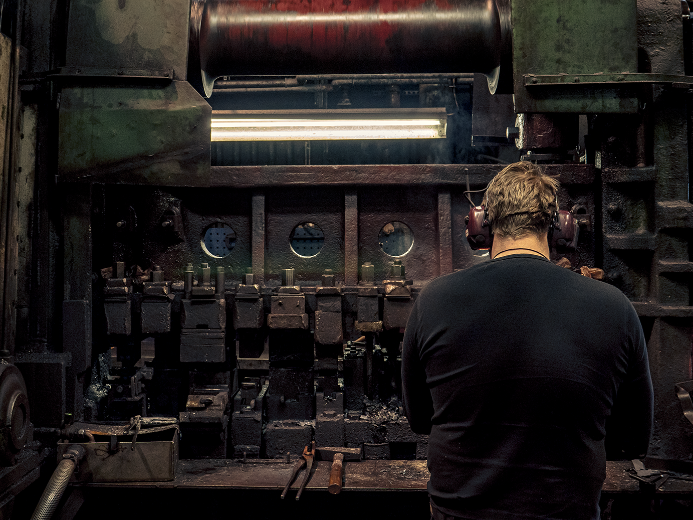 Blacksmith at work in the forge at Gränsfors Bruk, shaping a glowing axe head by hand.