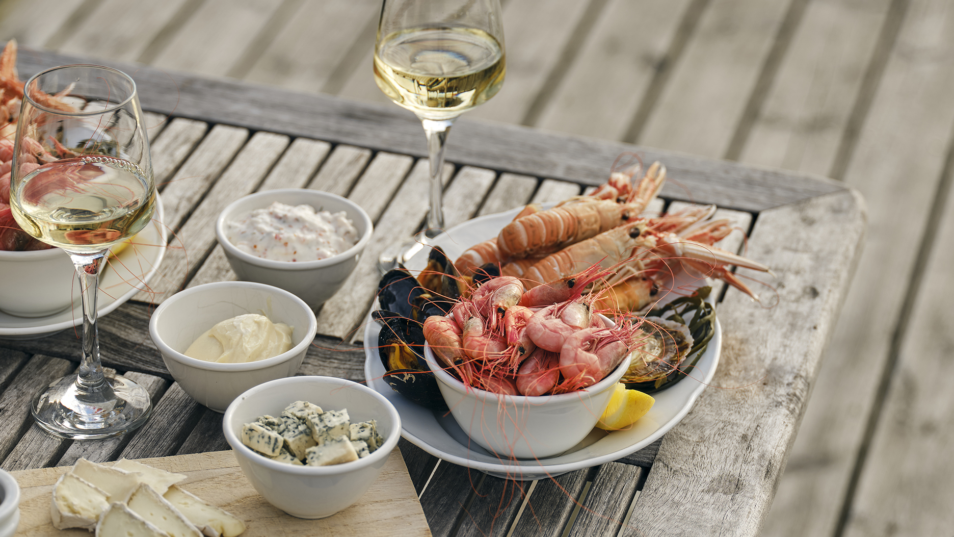 Een schaal met zeevruchten, bestaande uit garnalen, langoustines, mosselen en dipsauzen, geserveerd in de open lucht bij Everts Sjöbod in Grebbestad.
