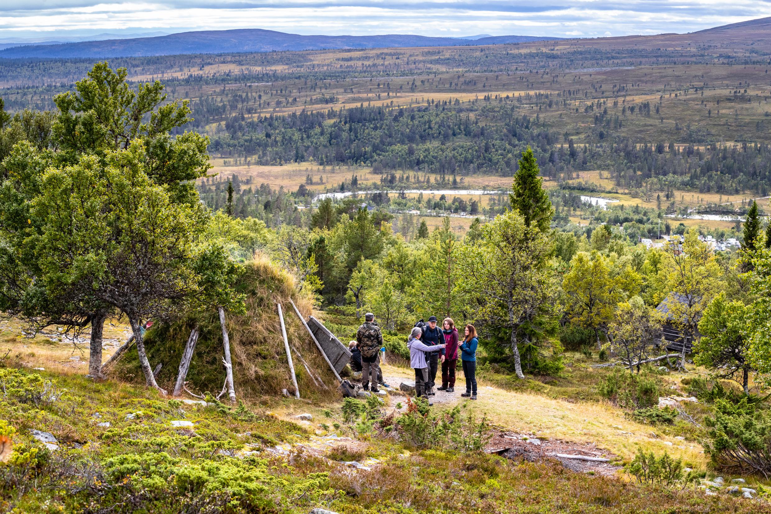 A group of hikers resting next to a hut in the nature in Dalarna. Mountains in the background.