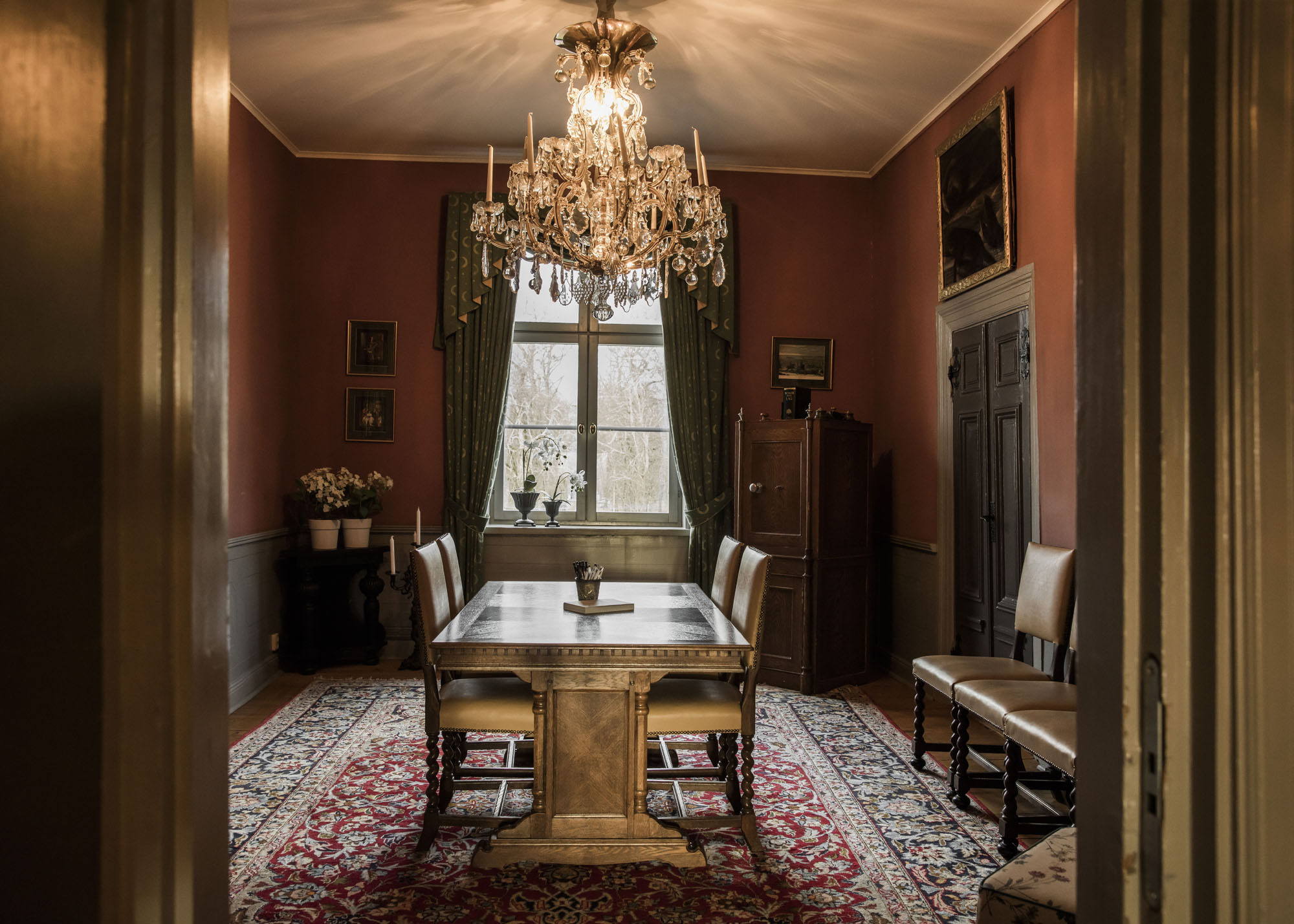 De oude eetkamer met kroonluchter, rode muren en oude meubels in het kasteel van Noors, waar ze zeggen dat koning Karel XII rondwaart.