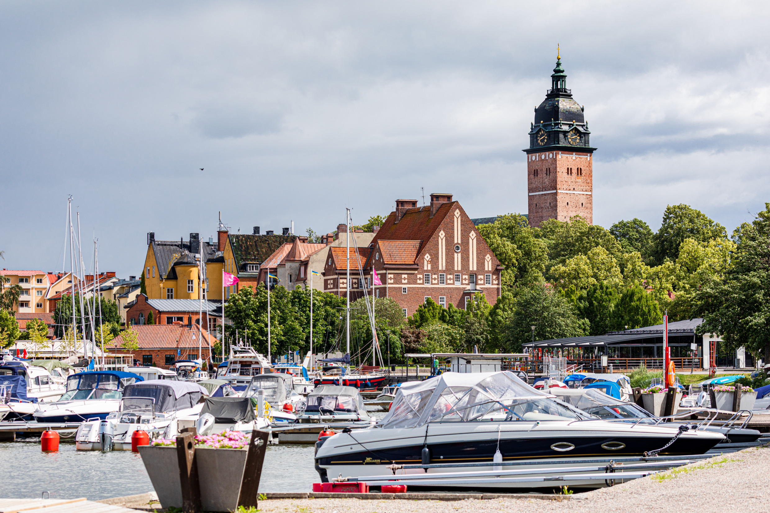 Des bateaux amarrés au port de Strängnäs, avec la ville et le clocher de l'église en arrière-plan.