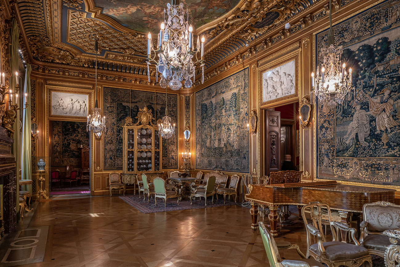 The Great Drawing Room at the Hallwyl Museum, with gilded woodwork, large tapestries, chandeliers, antique furniture and a grand piano.
