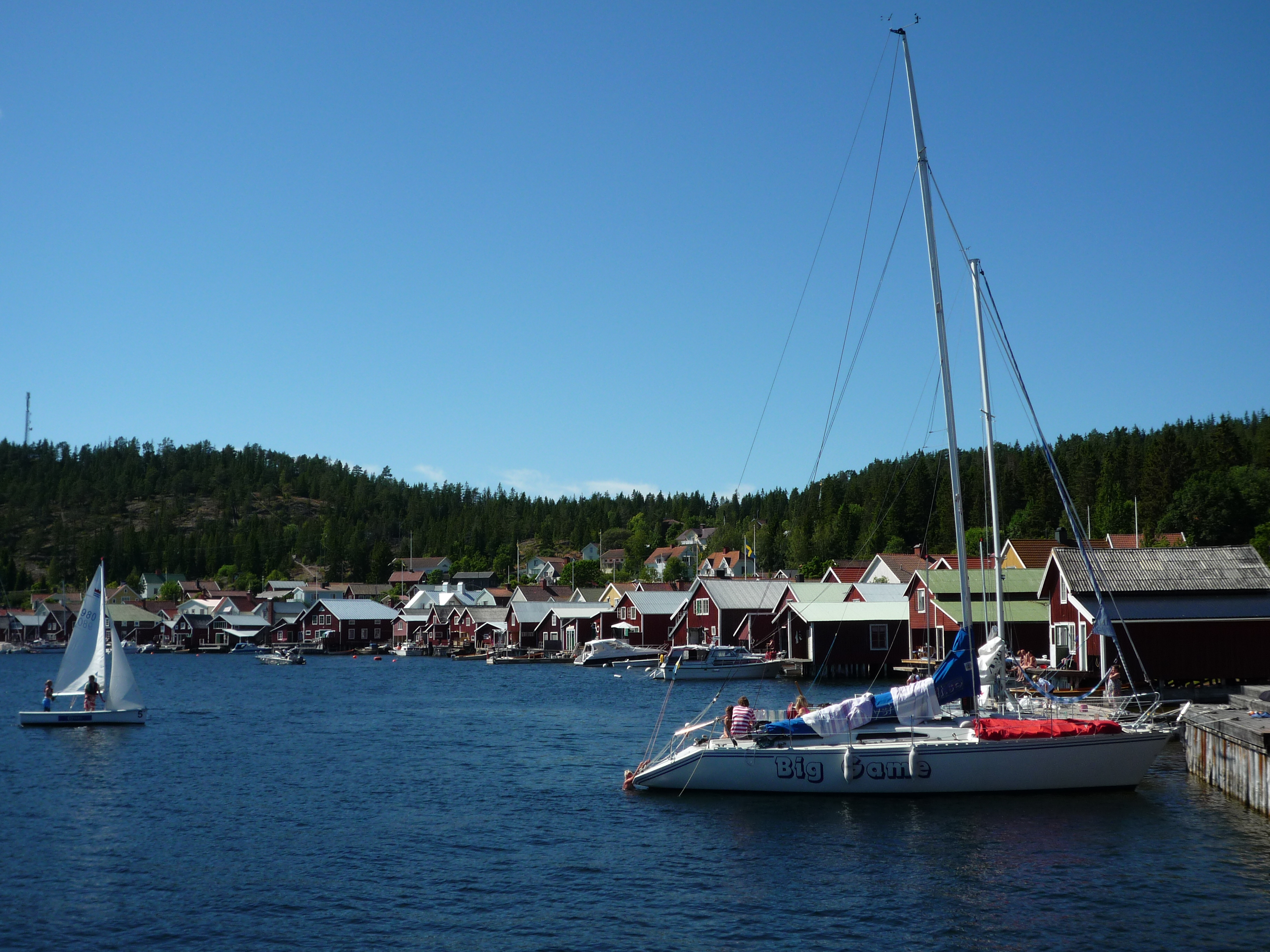 Un village et des cabanes à bateaux entourés de verdure et d'eaux calmes.