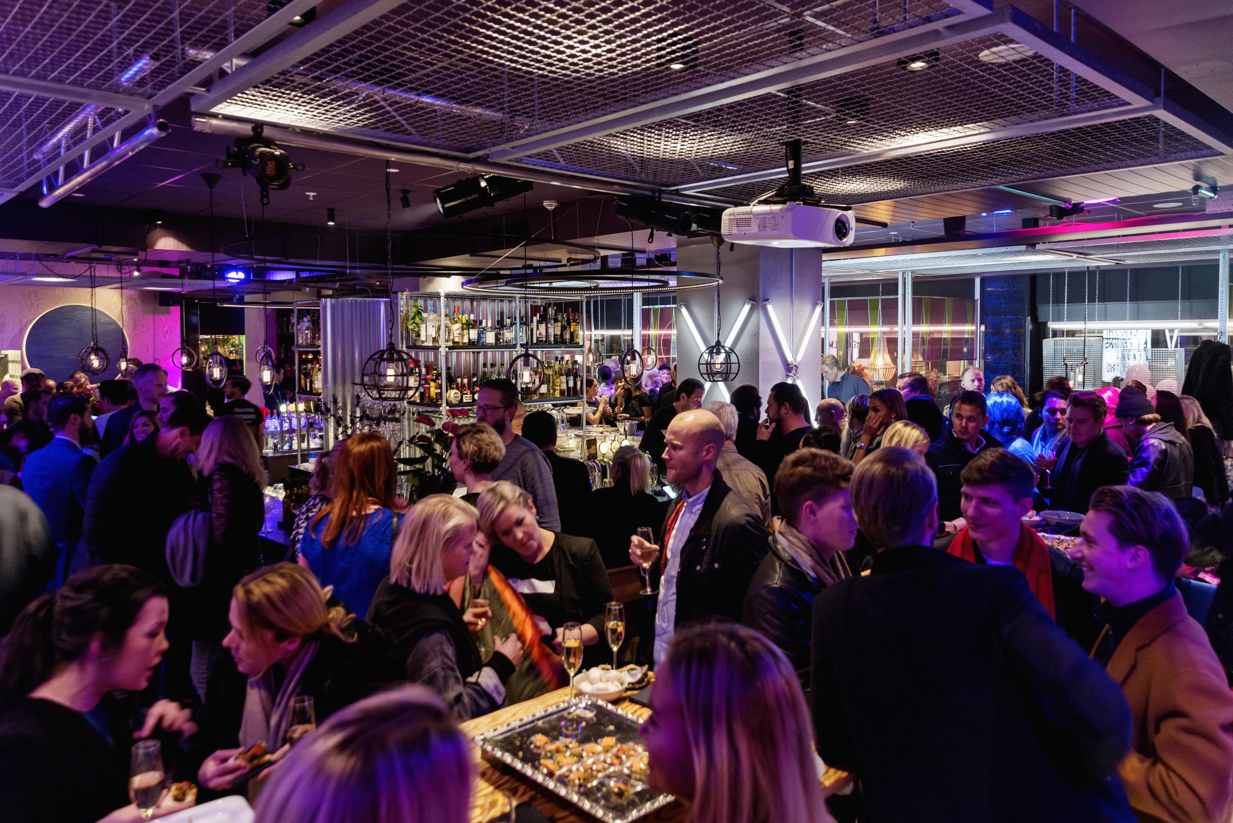 Het restaurant Bar Hilma staat vol met mensen die aan het eten, drinken en kletsen zijn.