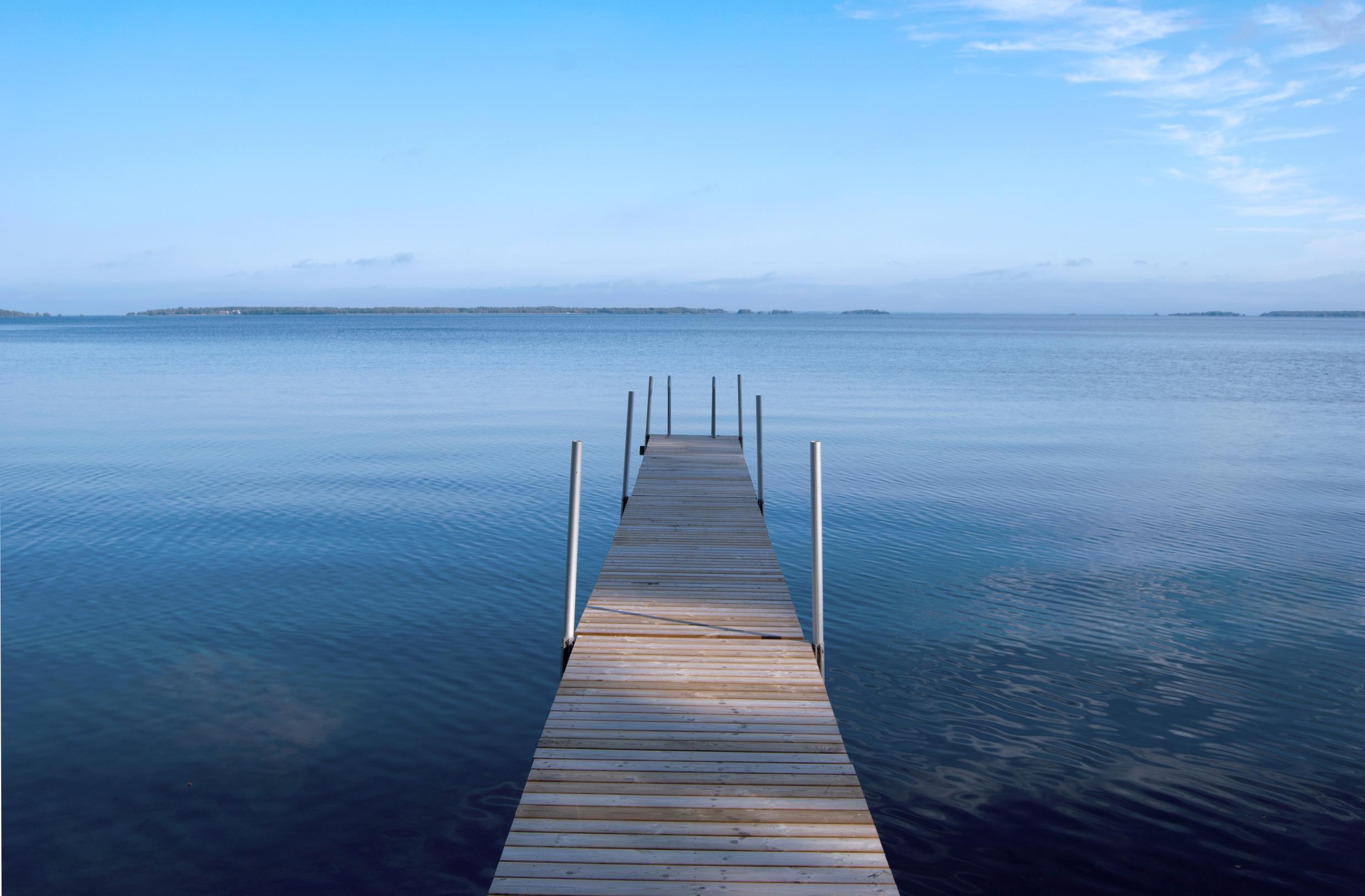 A jetty in a calm lake. Land in the horizon.
