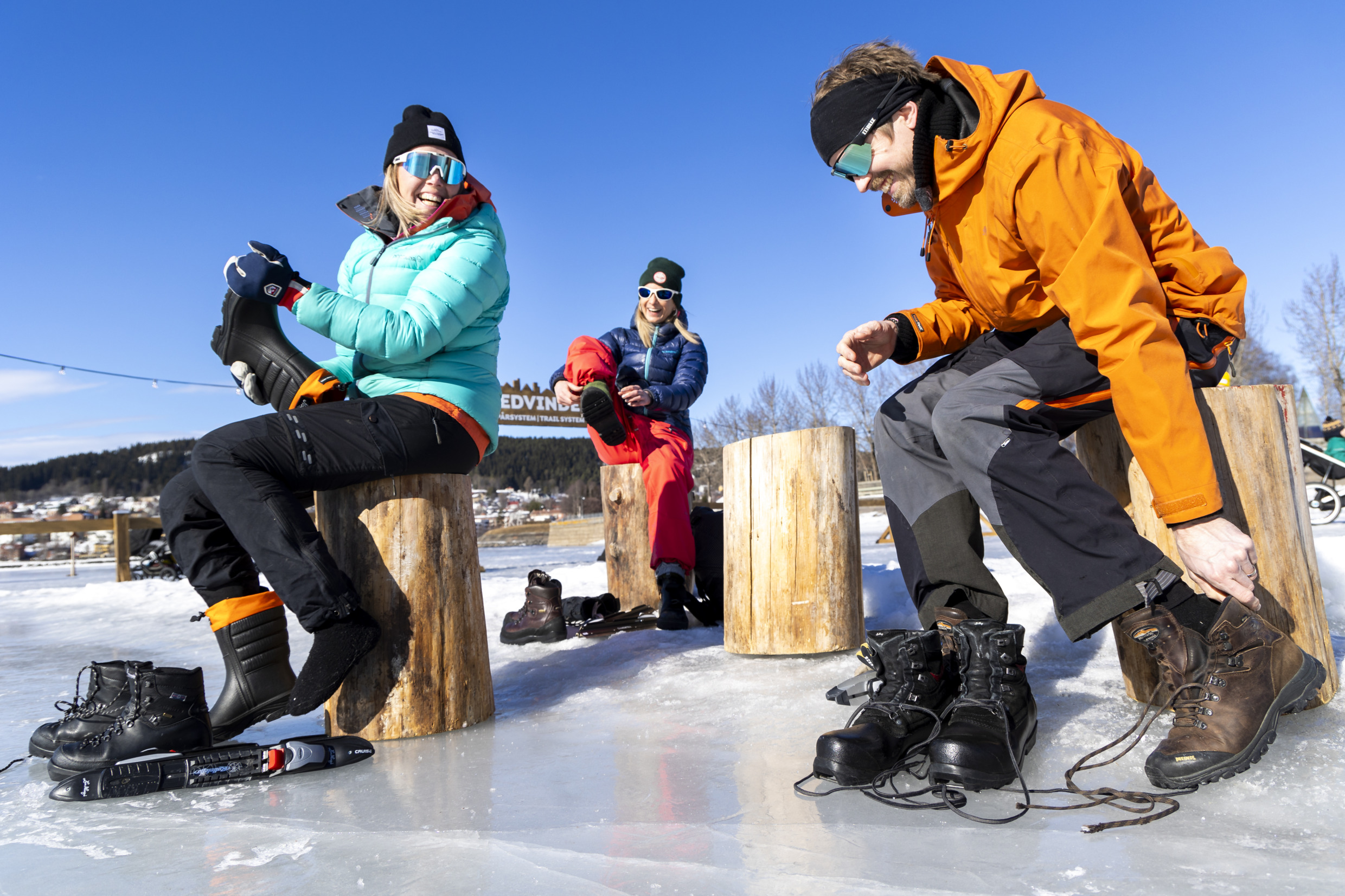 Three people put on long-distance ice skates.