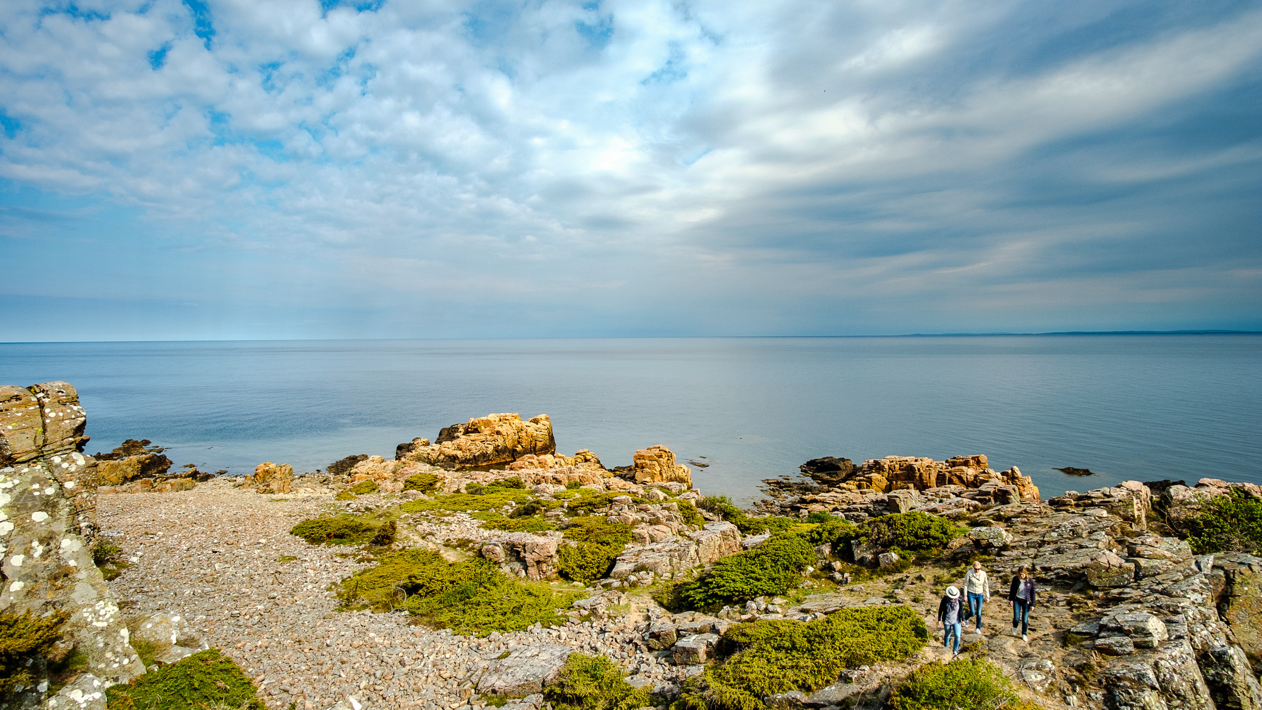 Vue sur la mer et les falaises de la réserve naturelle de Hovs Hallar. Trois personnes marchent sur la falaise.