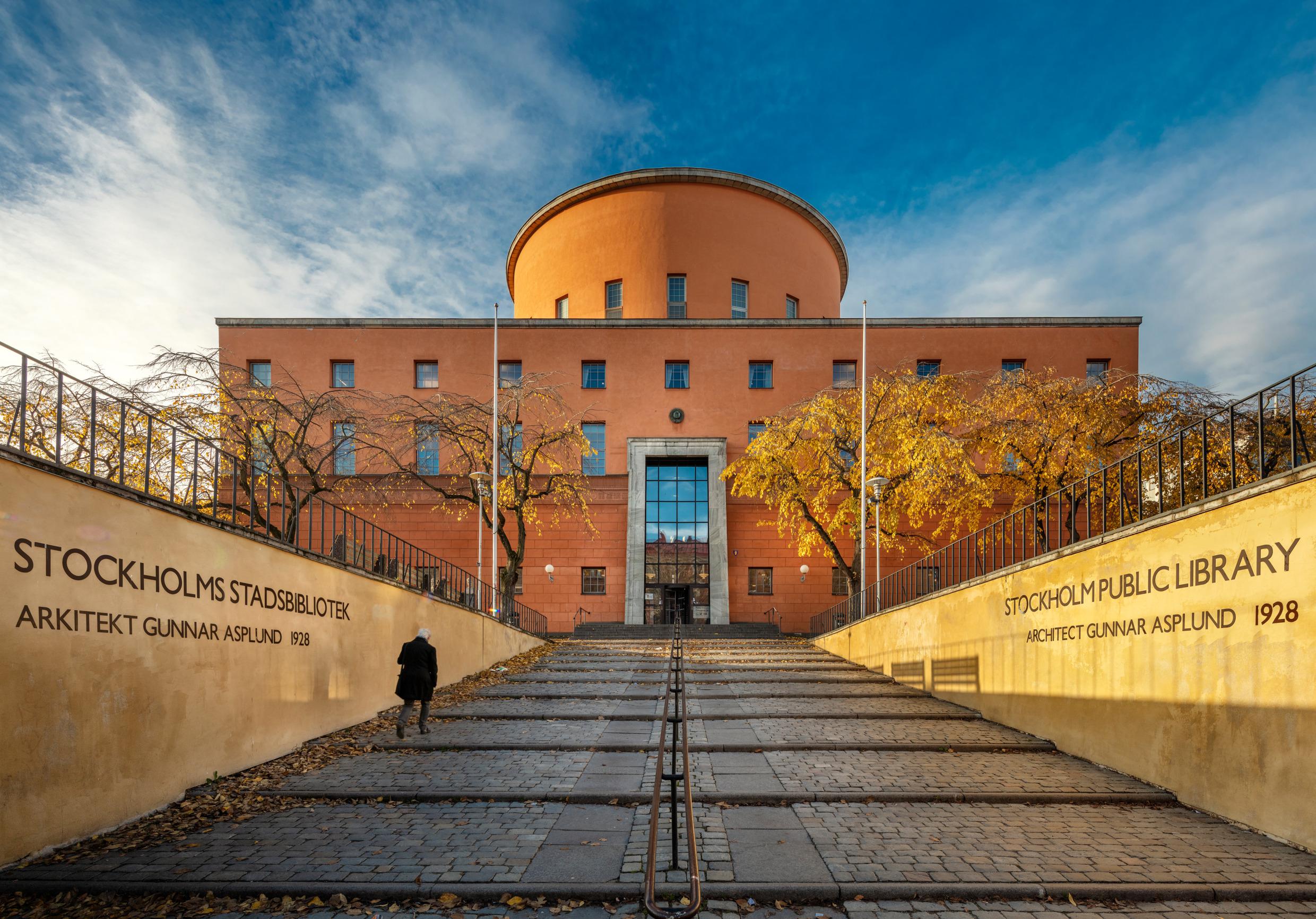 A wide walkway leads up to a rectangular building with a round tower in the centre.