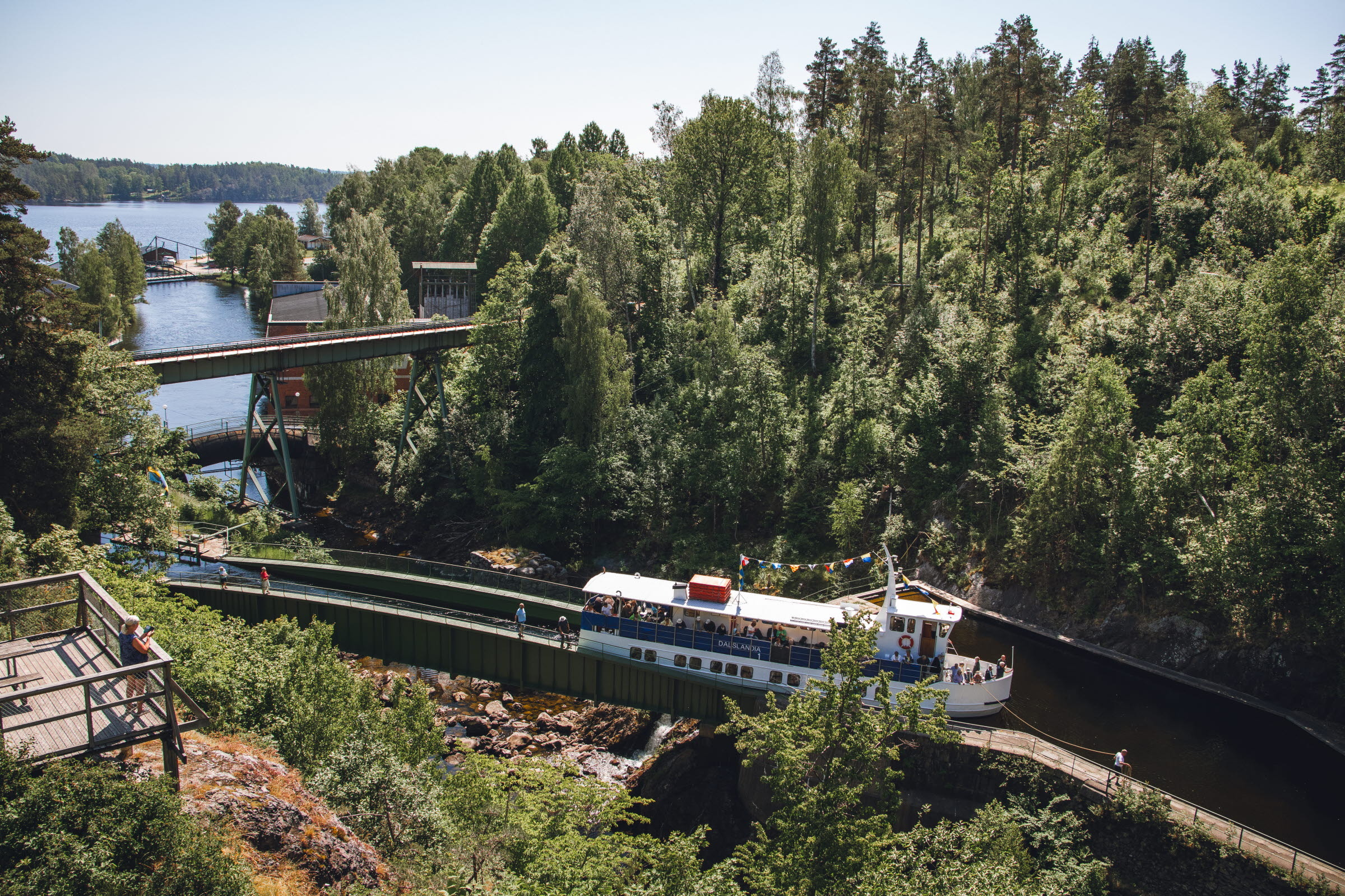 Passagiersboot vaart over het aquaduct in Håverud, onderdeel van het Dalslandkanaal, omringd door groen bos en bruggen erboven.