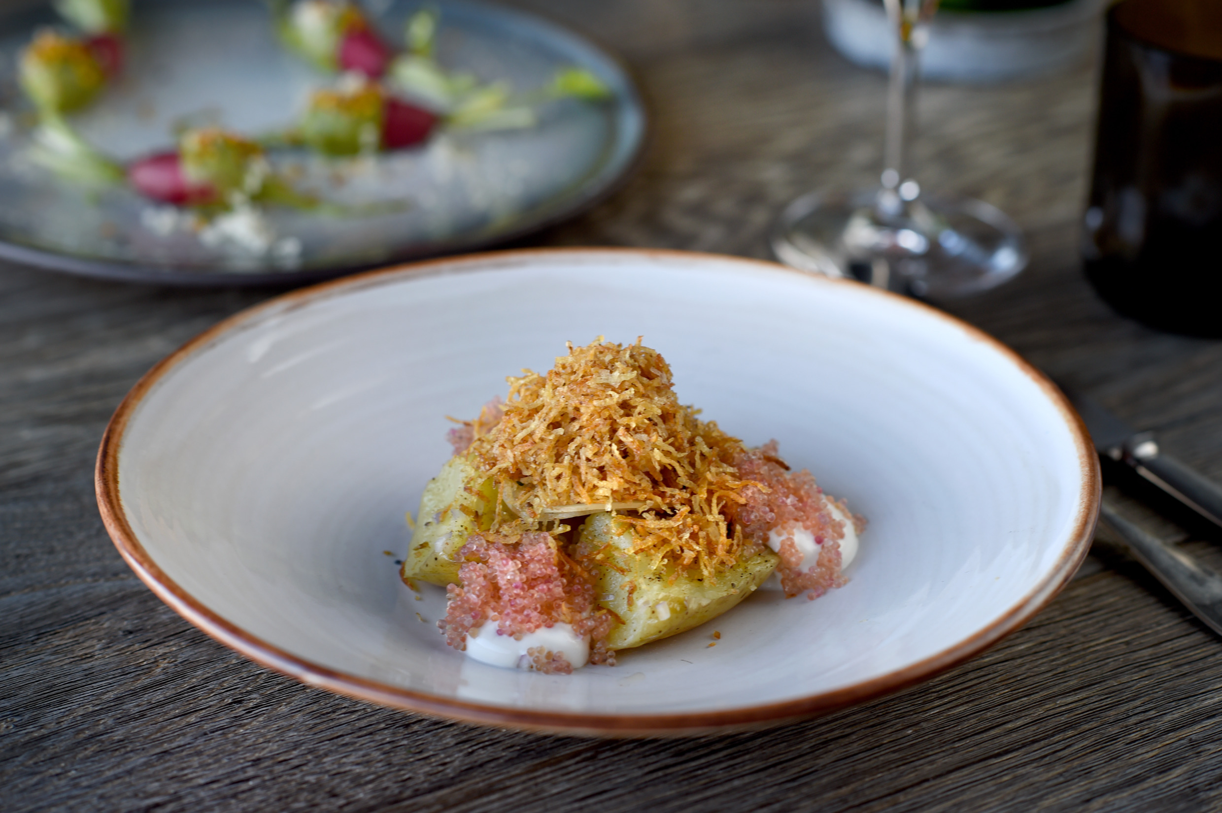 Ein weißer Teller mit Essen, das Kartoffeln und Rogen enthält.